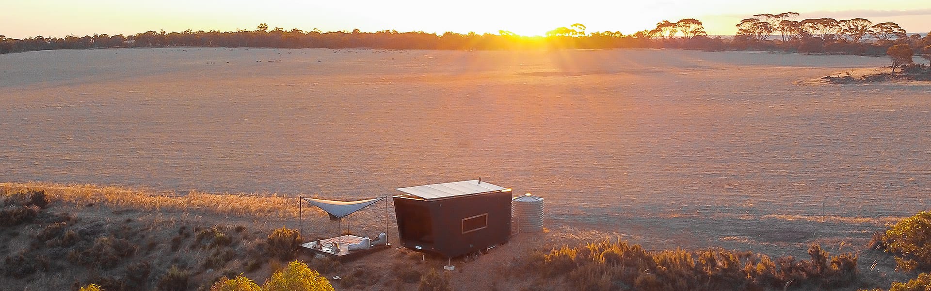A tiny cabin in Wheatbelt field at sunset