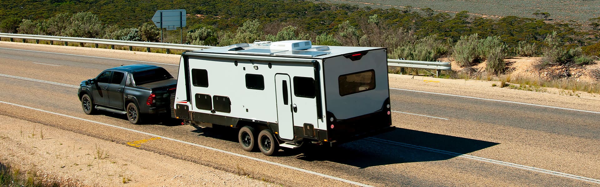 A four-wheel drive towing a caravan along a sealed country road