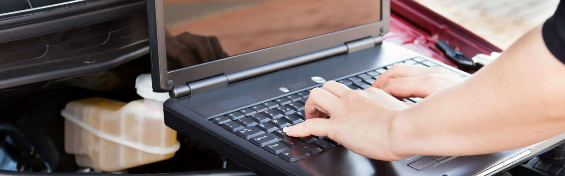 A man typing on a computer over an engine