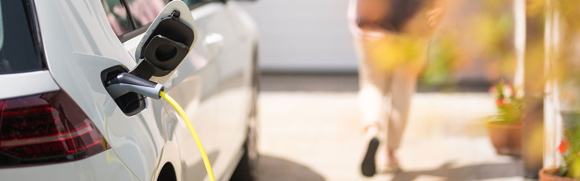Charging electric car with woman in the background