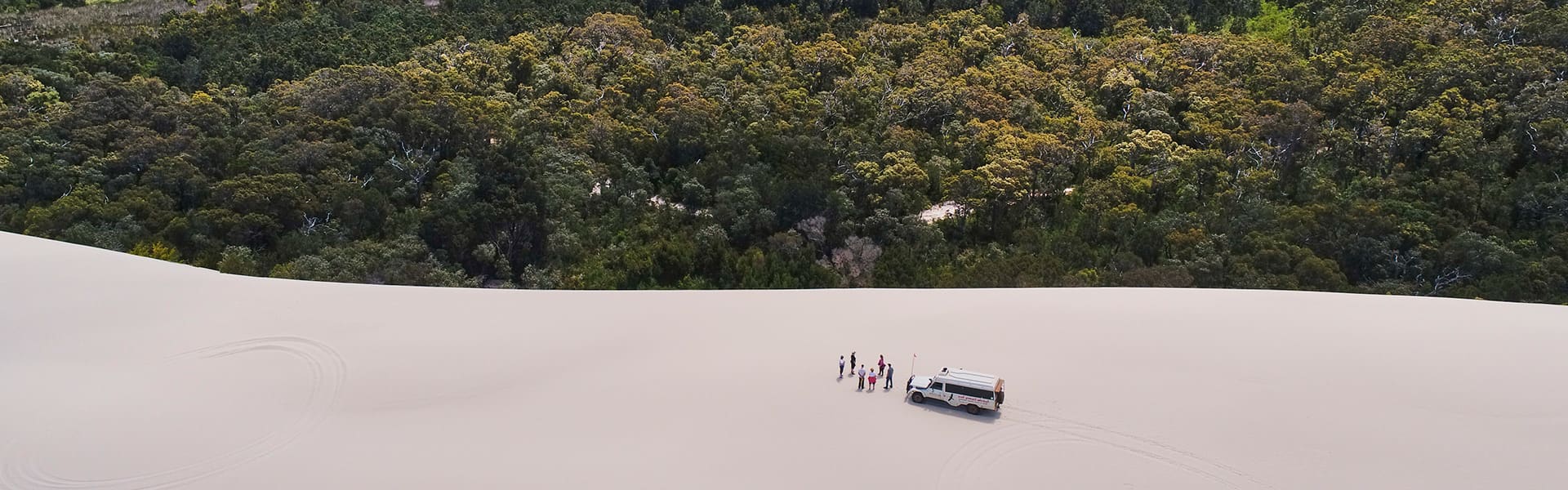 Car and people on a sand dune