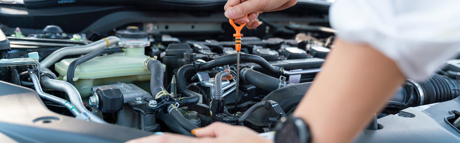 Woman checking car oil stick