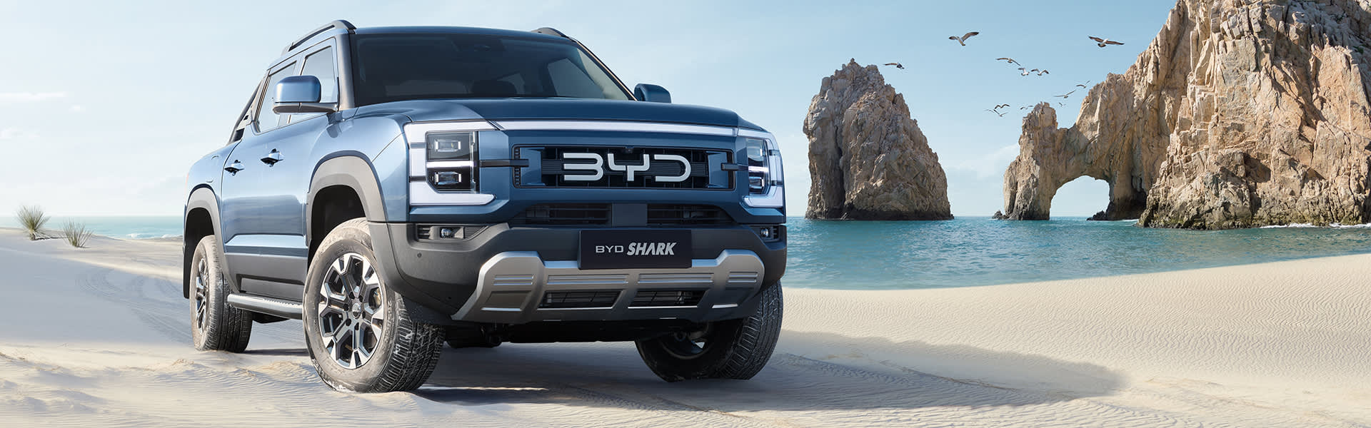 A blue BYD shark ute on a white sand beach