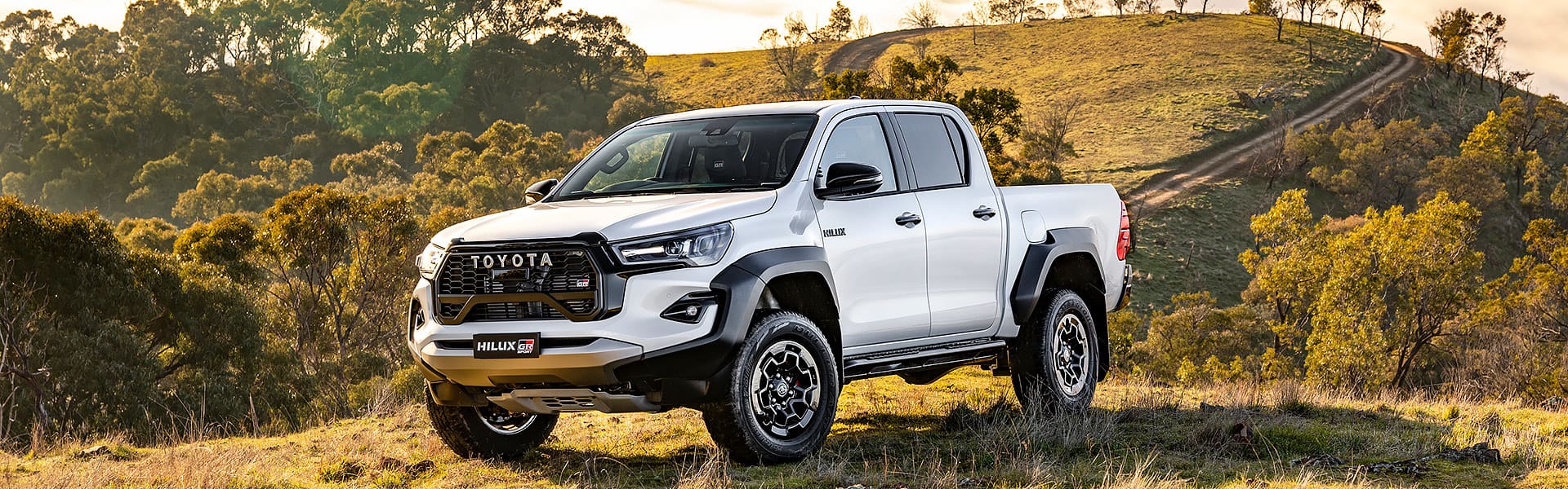 A white Toyota HiLux in a farmland setting