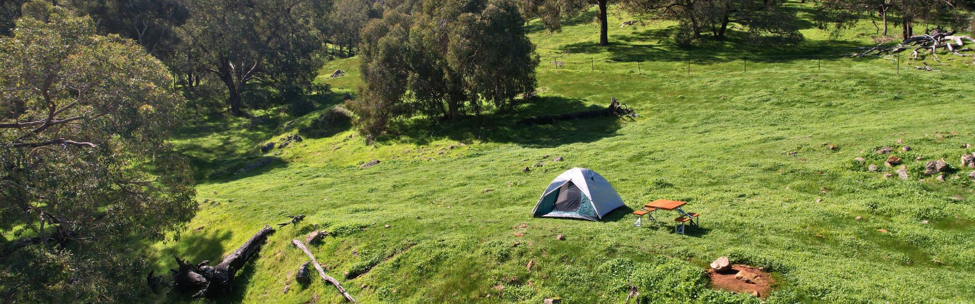 Small tent set up on green countryside
