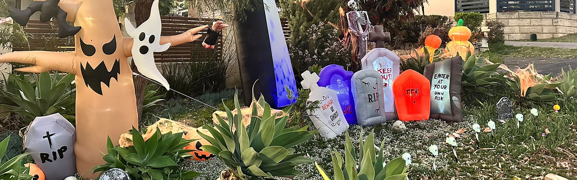 An inflatable ghost and headstones on a front lawn