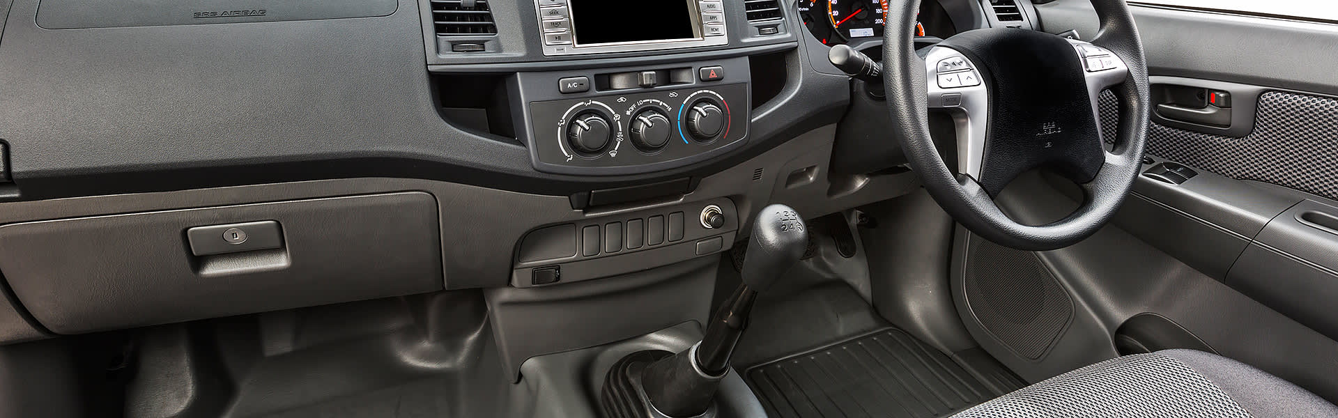 The interior of a car showing dashboard, steering wheel and gear stick