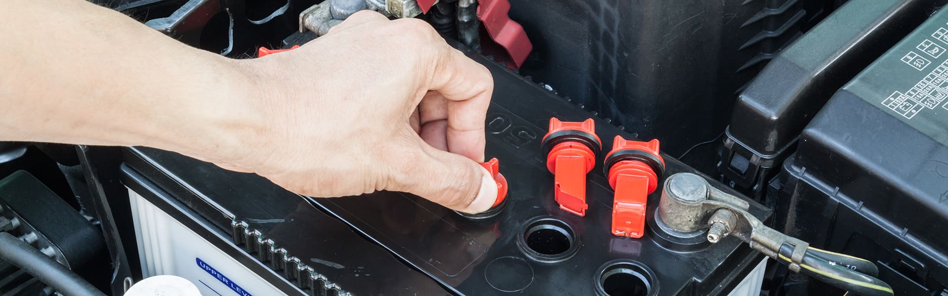 Person lifting cap on a car battery