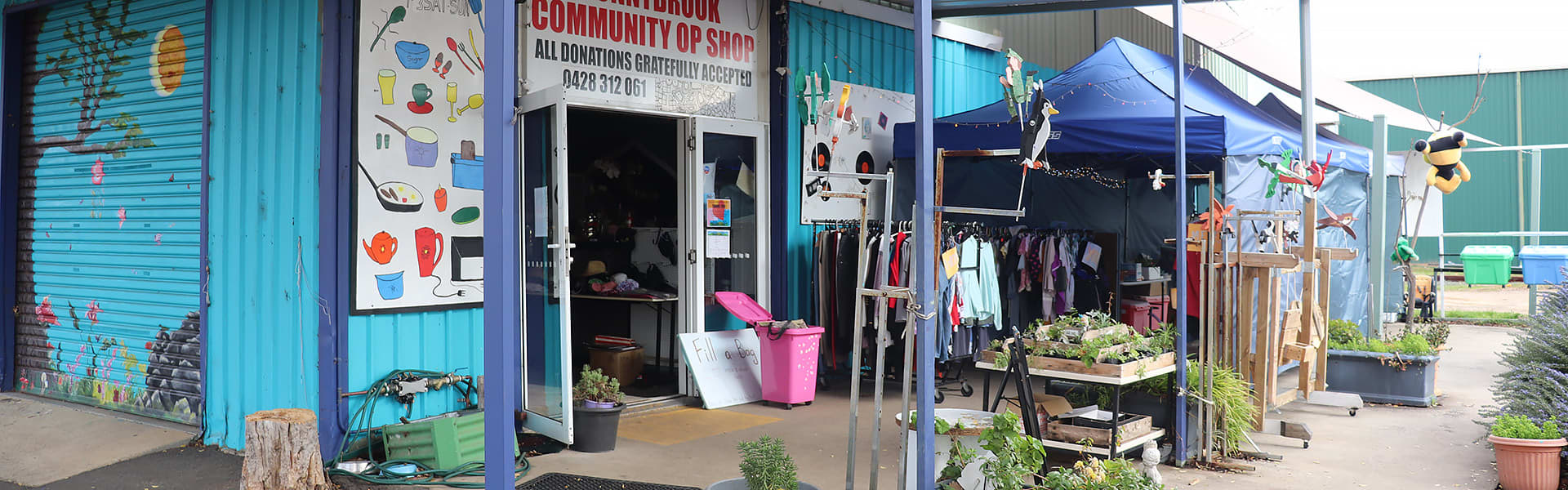 The outside of an op shop painted bright blue with goods outside
