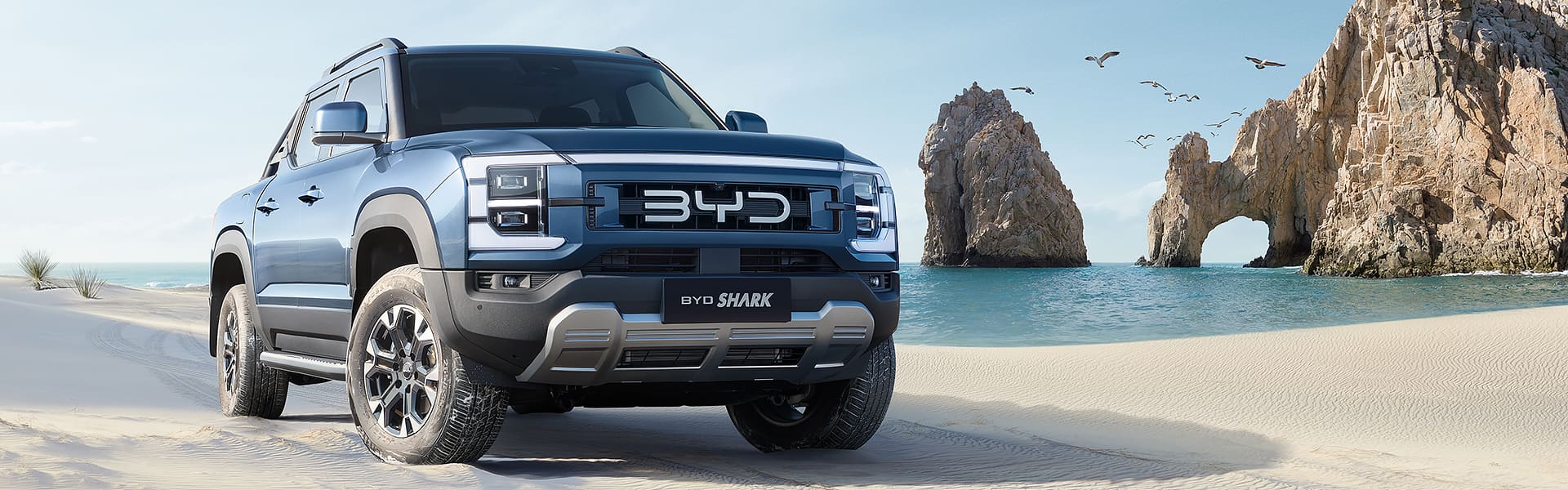 A blue BYD shark parked on a white-sand beach