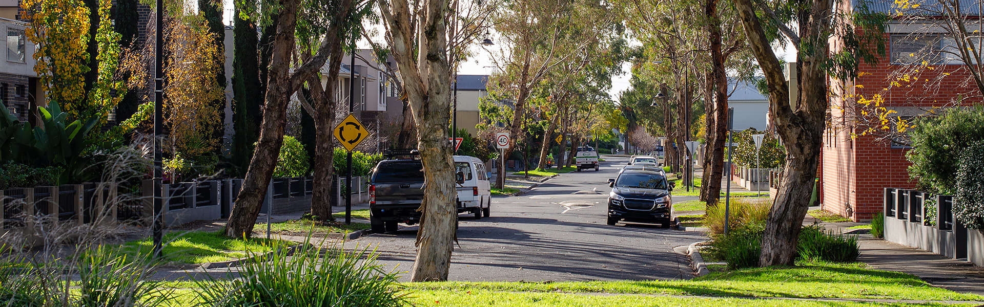 A wide view of a suburban street with cars parked in front of homes