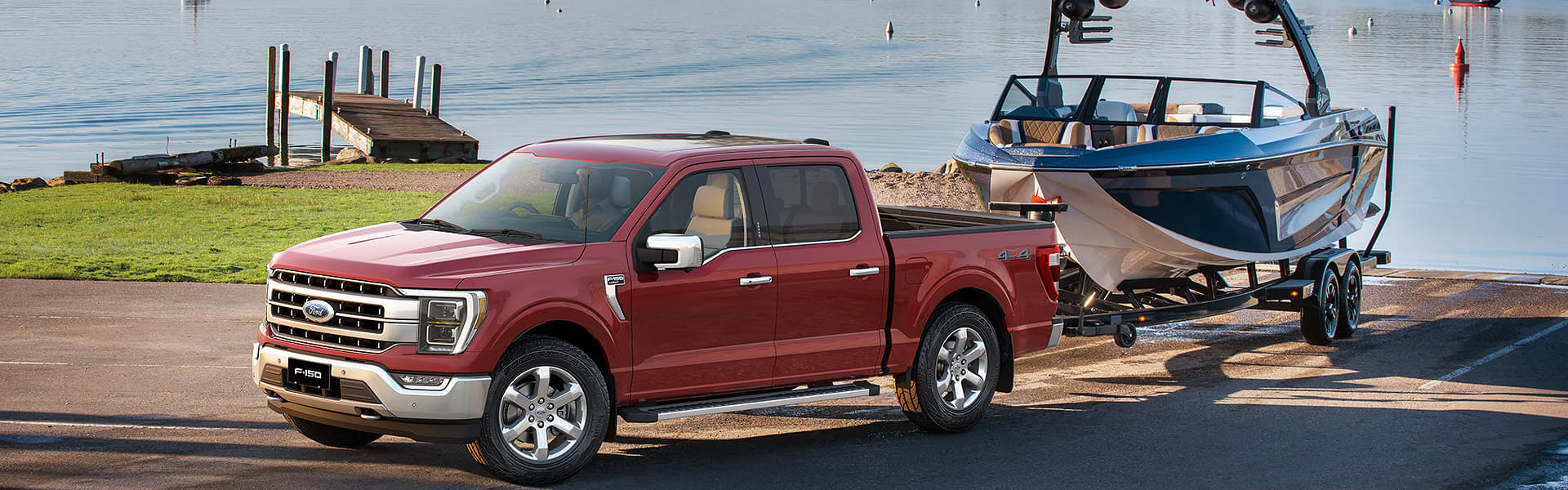 A red Ford F-150 towing a boat from a boat ramp