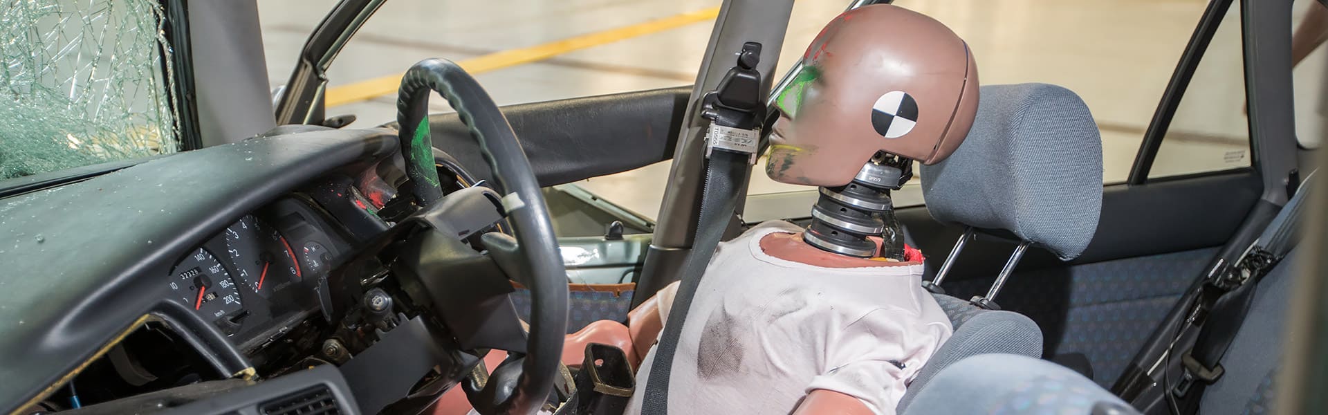 A crash test dummy in the driver's seat of a crashed car