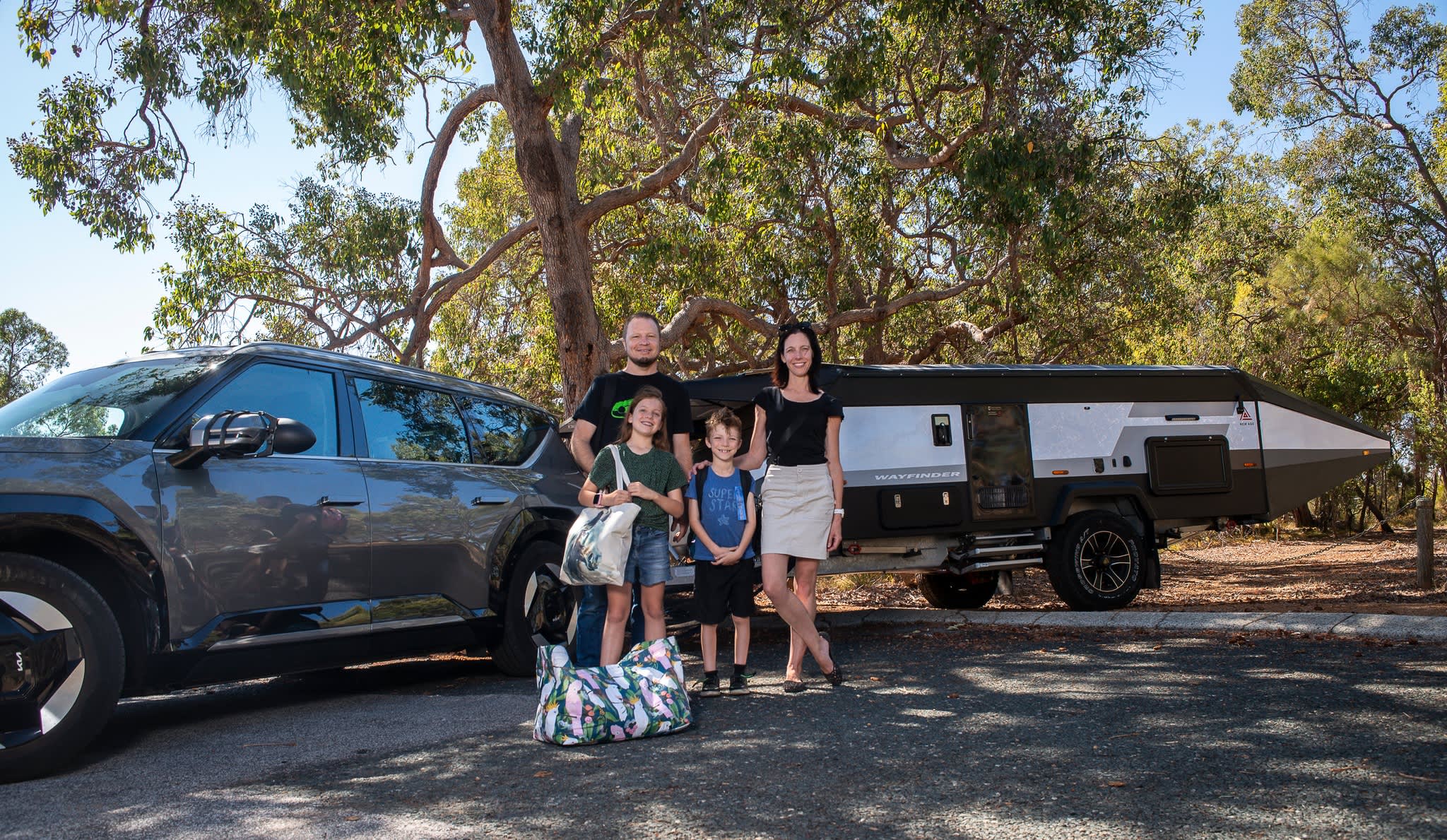 The McLennan Family posing with their EV and caravan