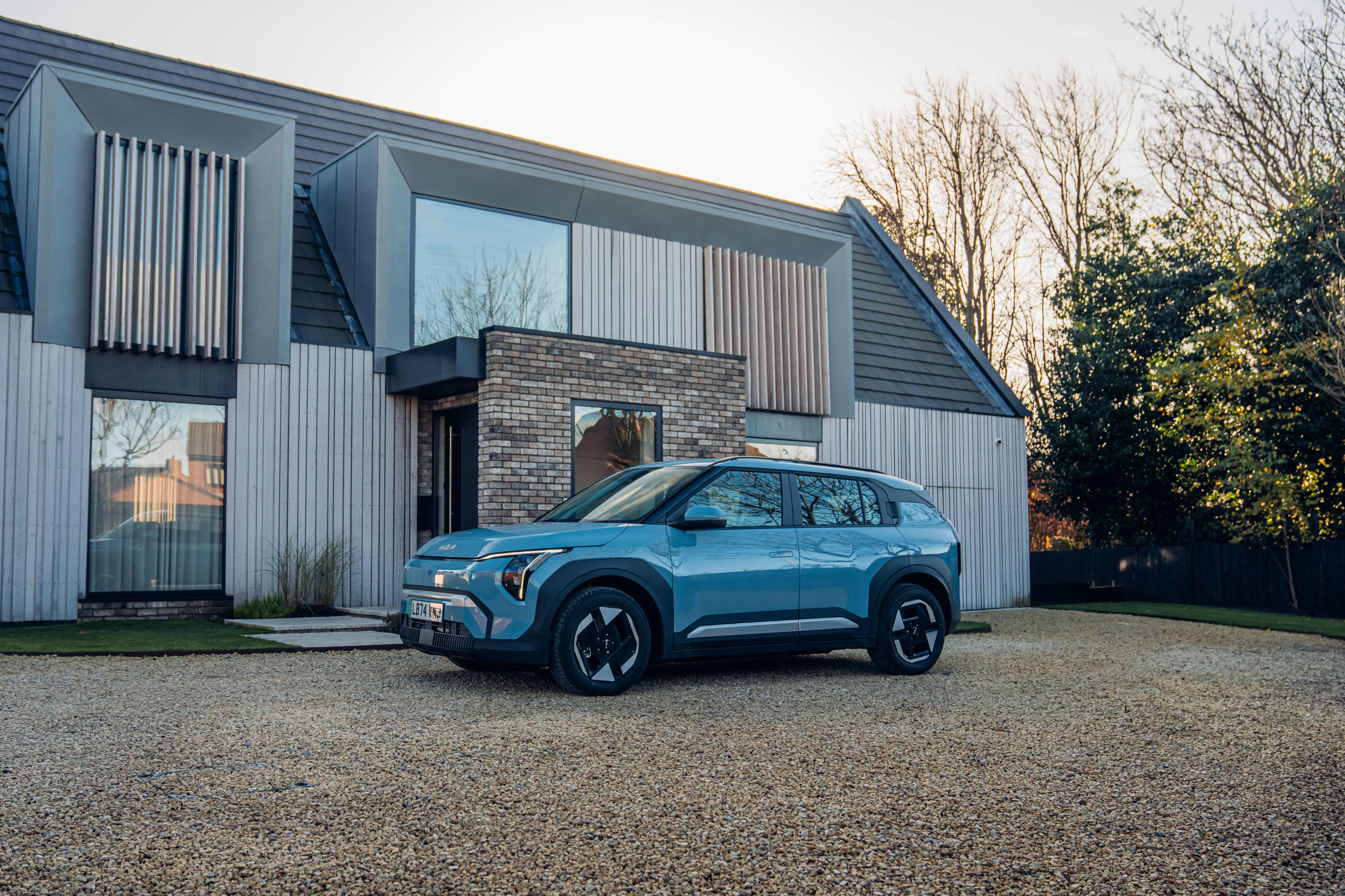 A blue Kia EV3 parked outside a home