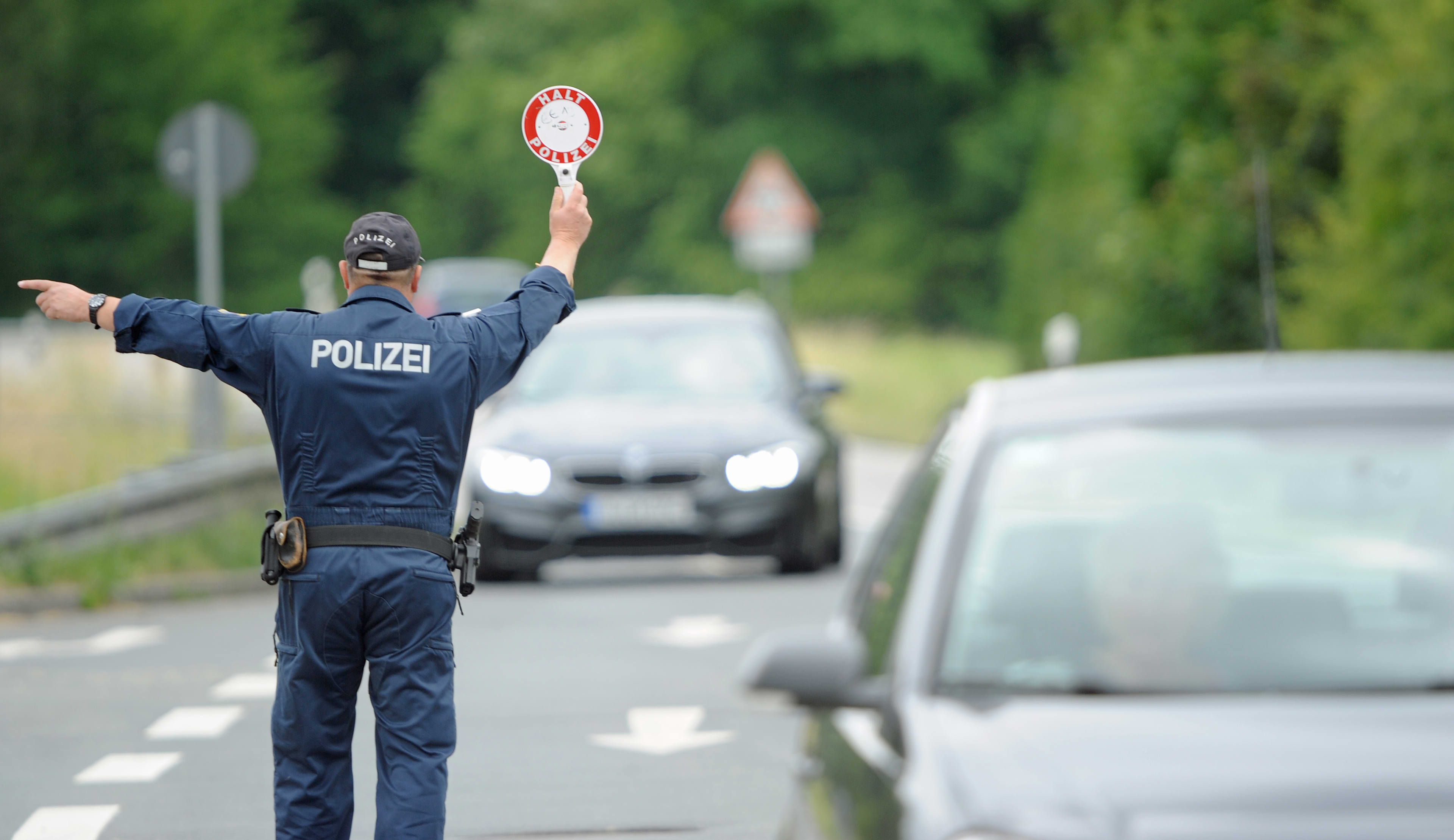 A police officer on a road waves a motorist over to stop