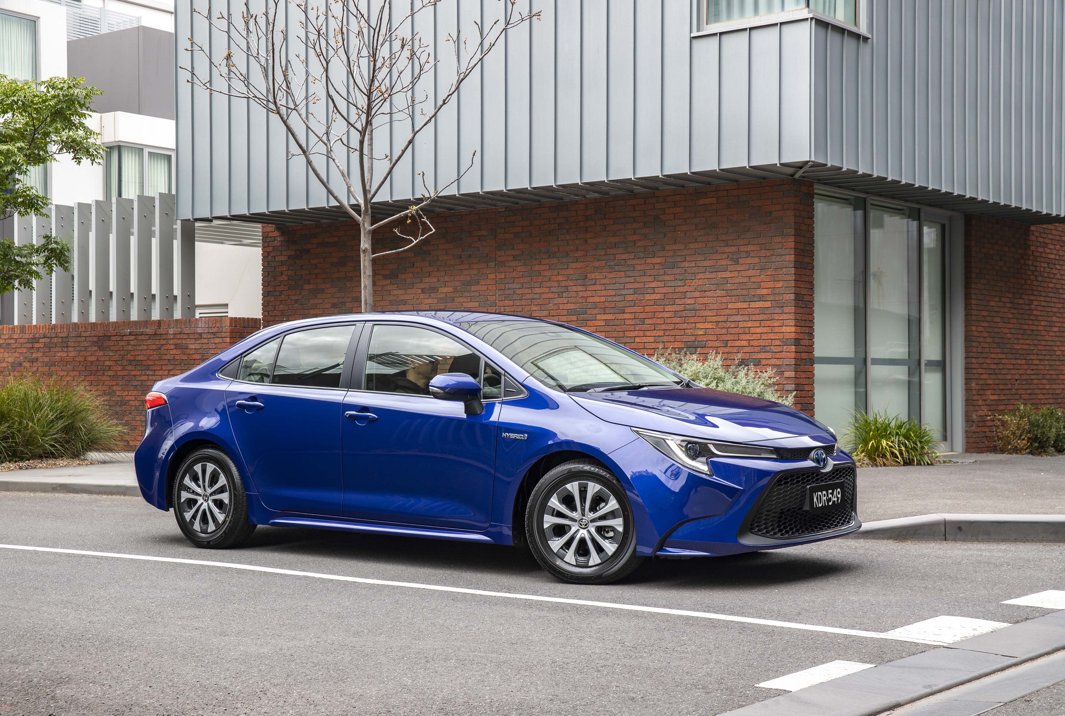 A blue Toyota Corolla at the intersection of a city street