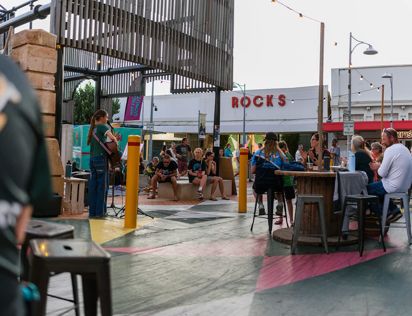 People seated at an outdoor space listening to live music.