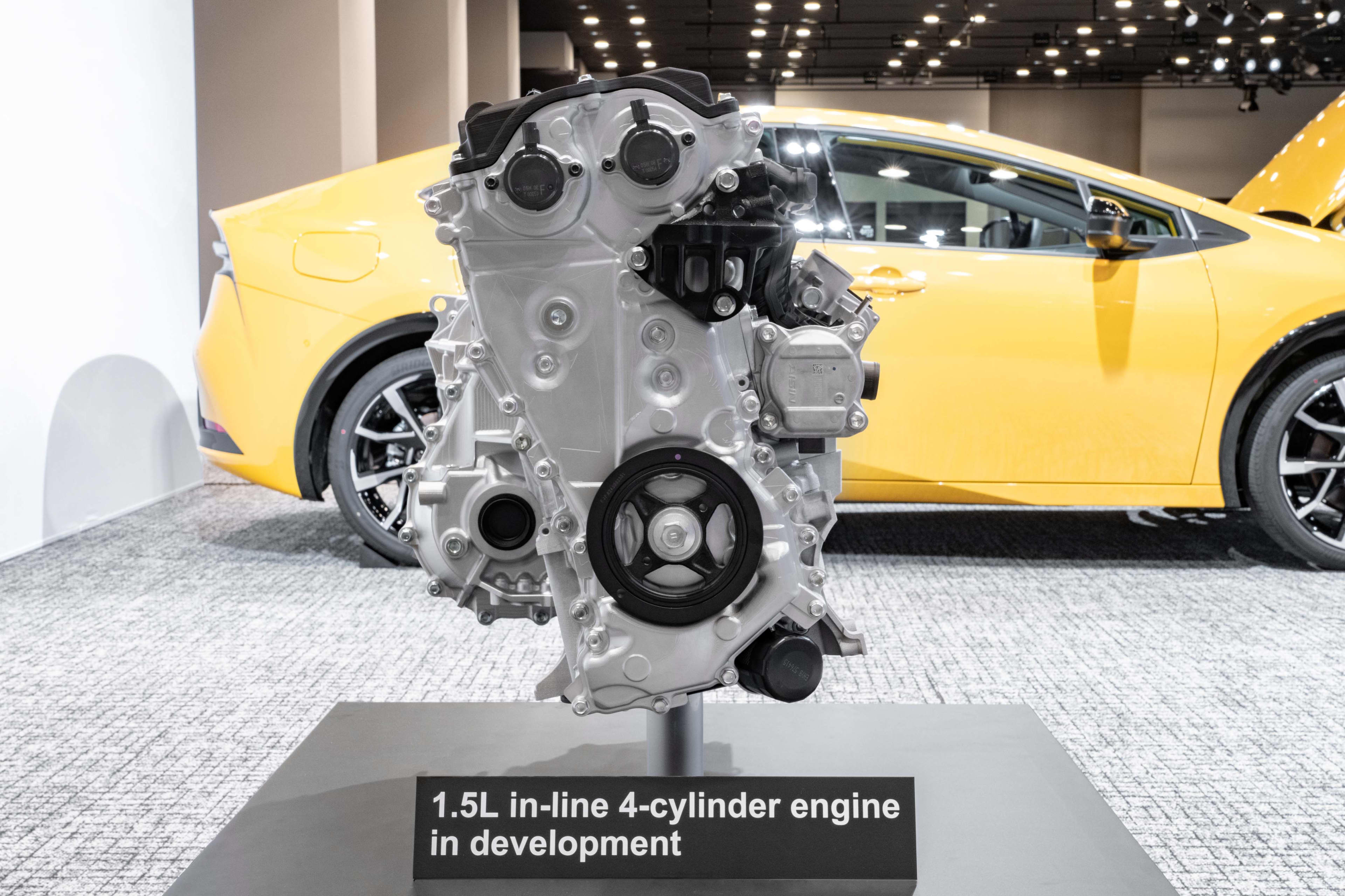 A Subaru engine on a stand in front of a yellow car