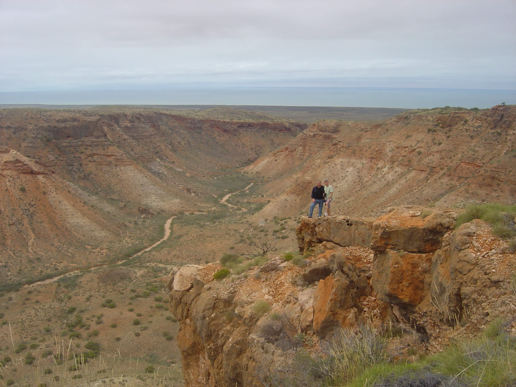 Two hikers standing at the edge of a cliff in Cape Range National Park, Western Australia