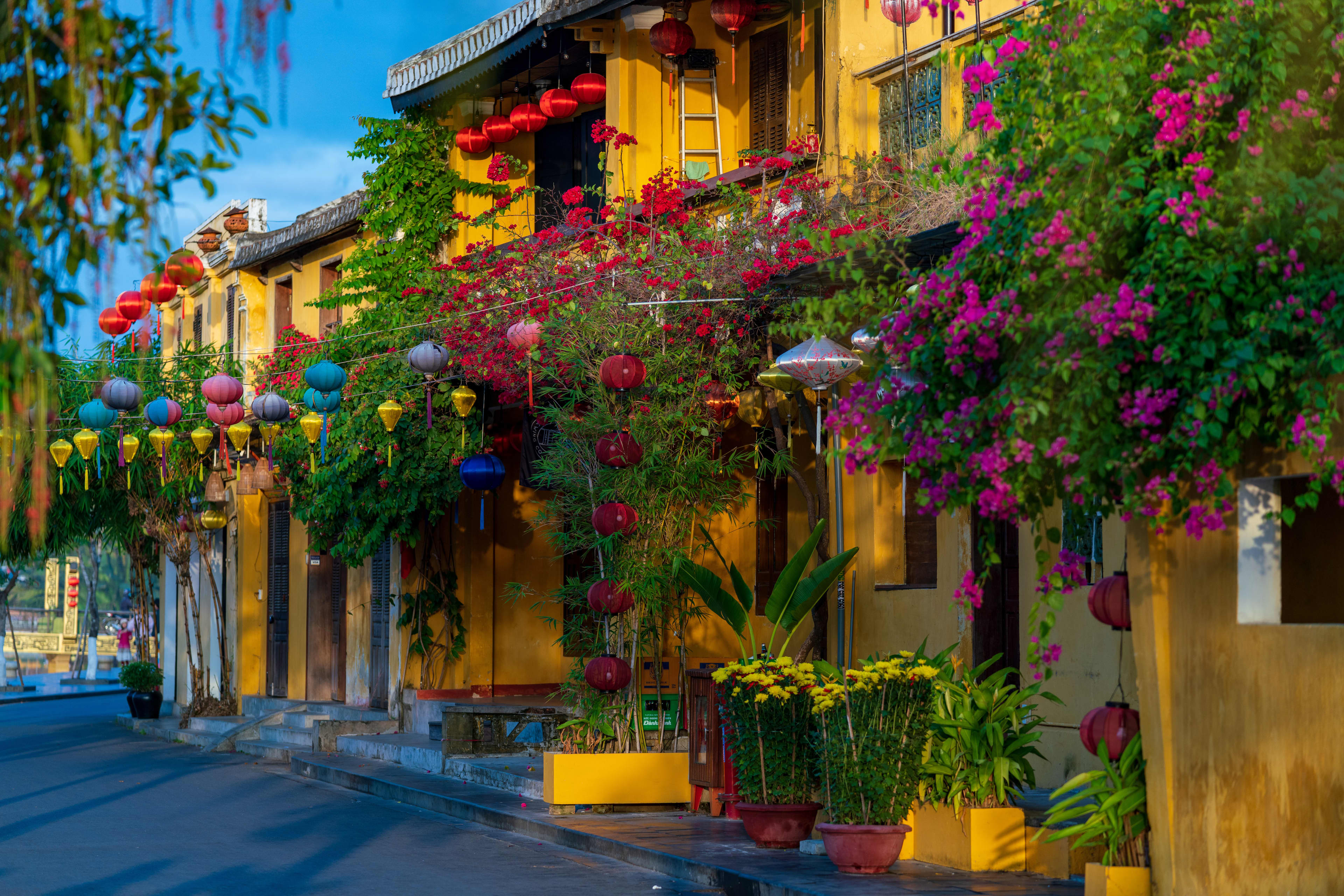 Yellow buildings covered in climbing flowers and lanterns in Hanoi Old Town.