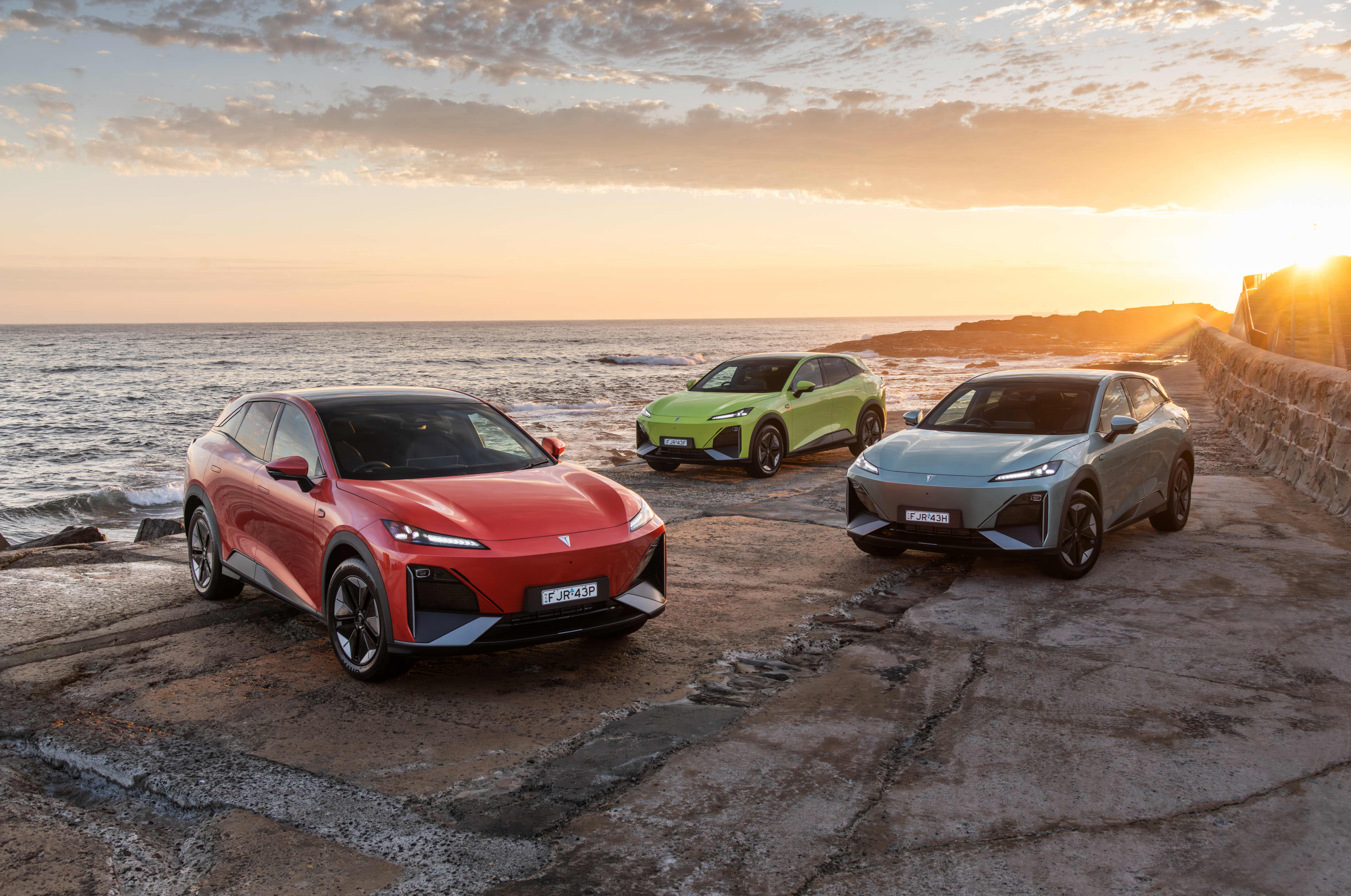Three Deepal electric vehicles parked in front of a beach at sunset