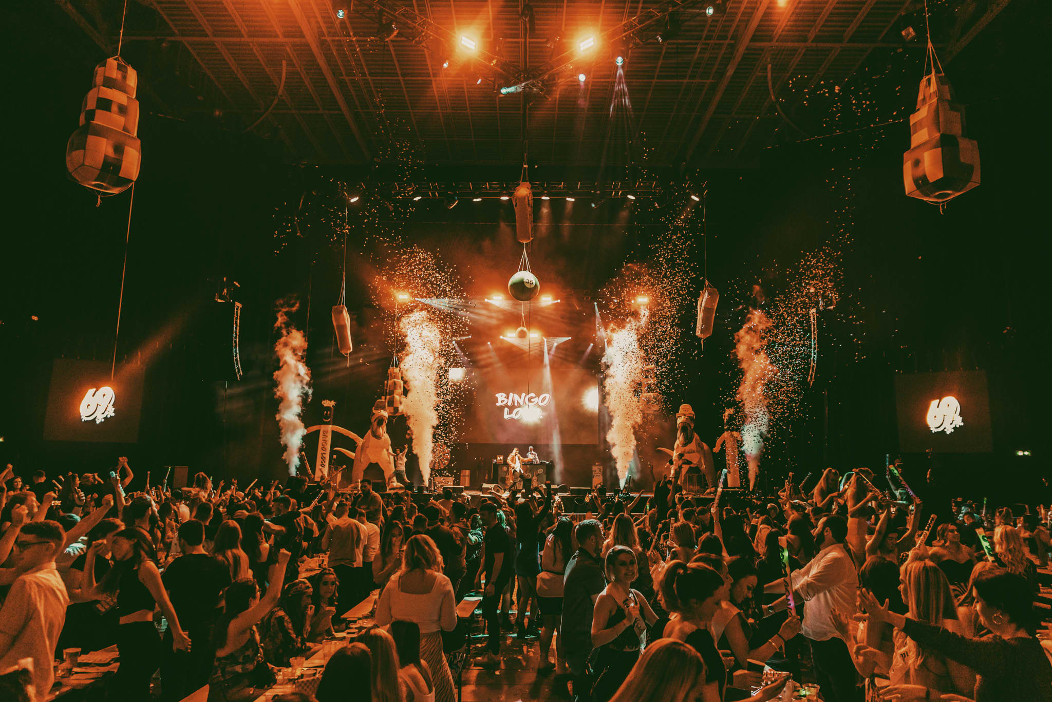 Night time rave with many people dancing under neon lights with confetti in the air
