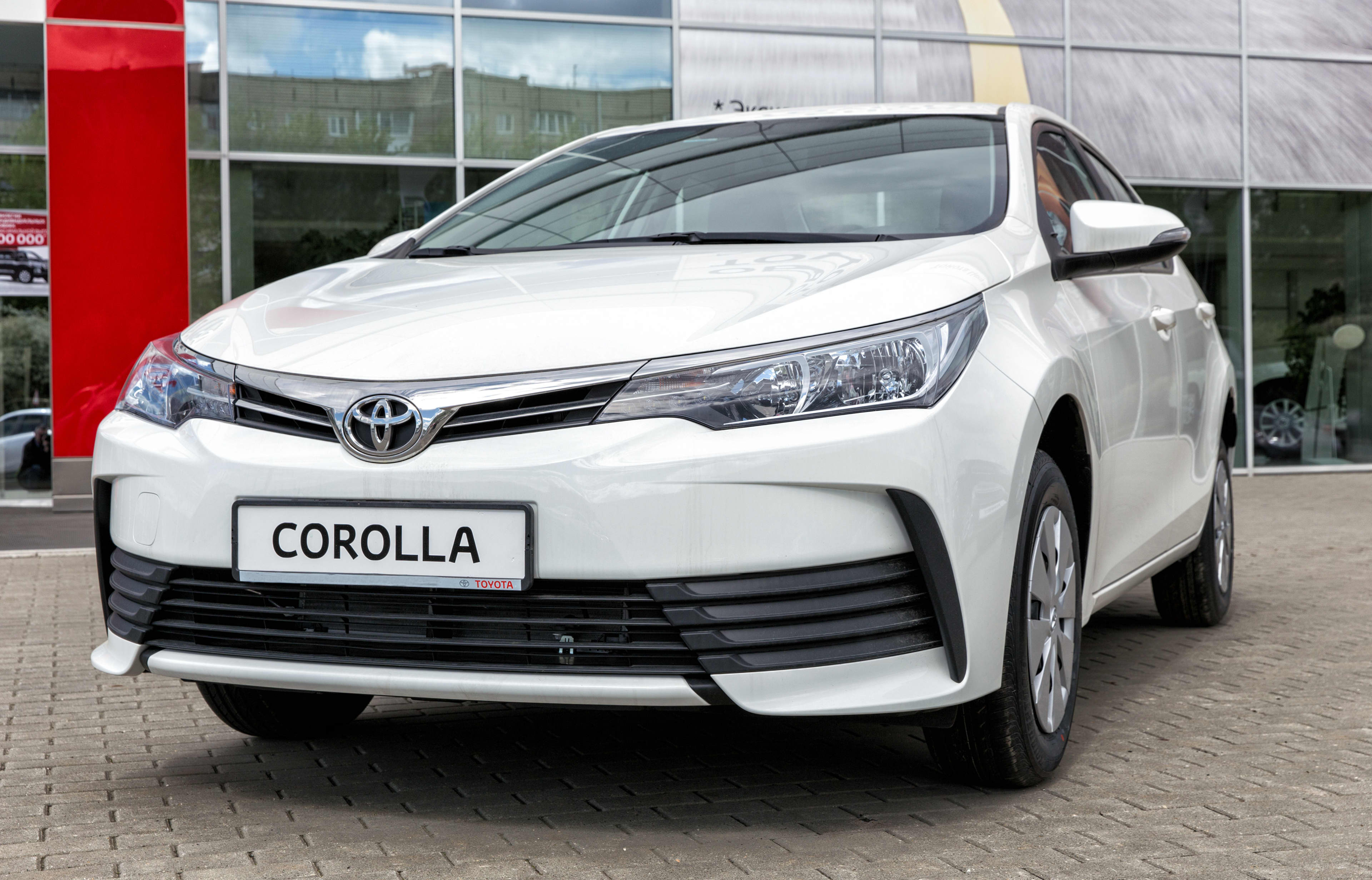 A white Toyota Corolla parked outside a car dealership