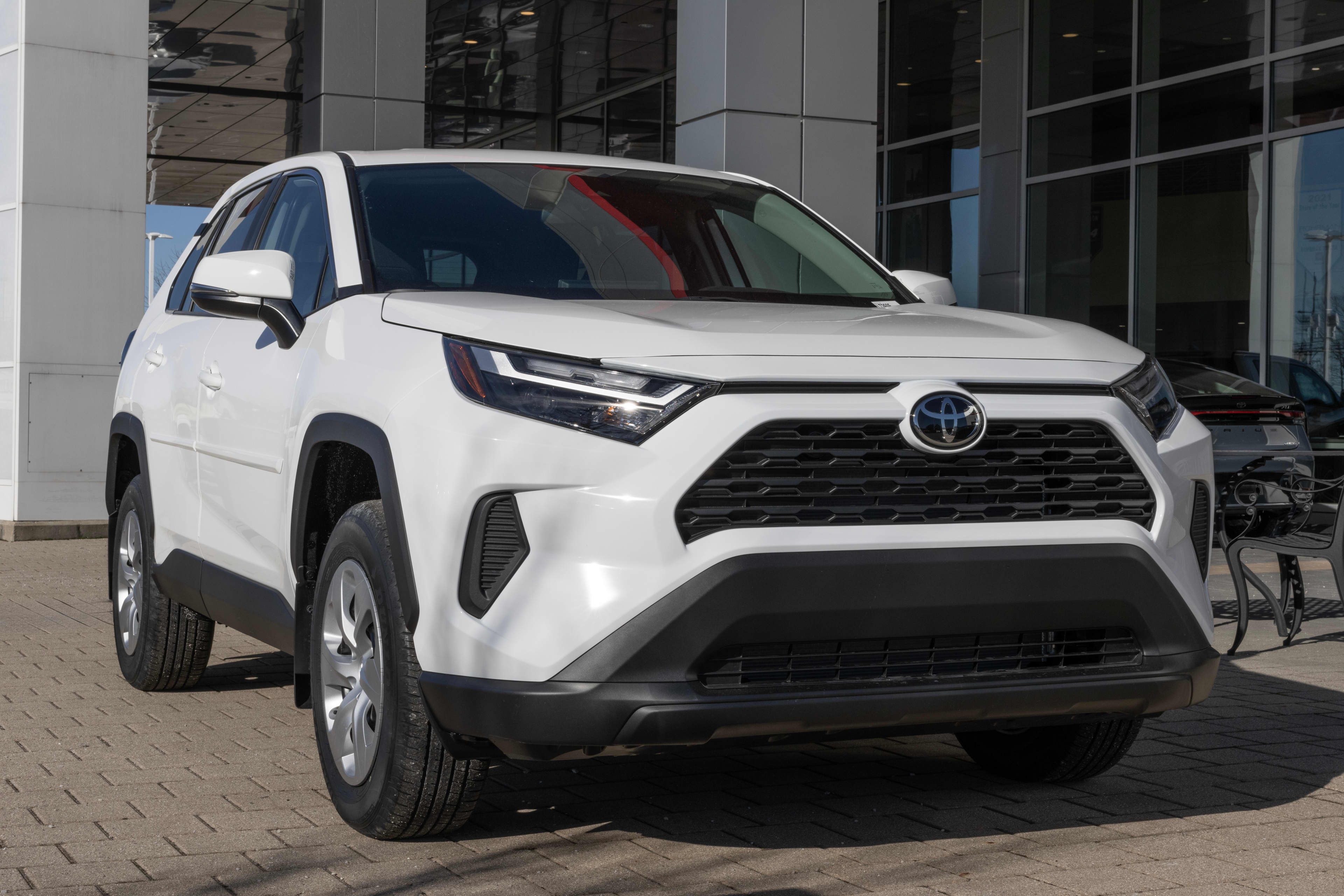 A white Toyota RAV4 parked outside a car dealership