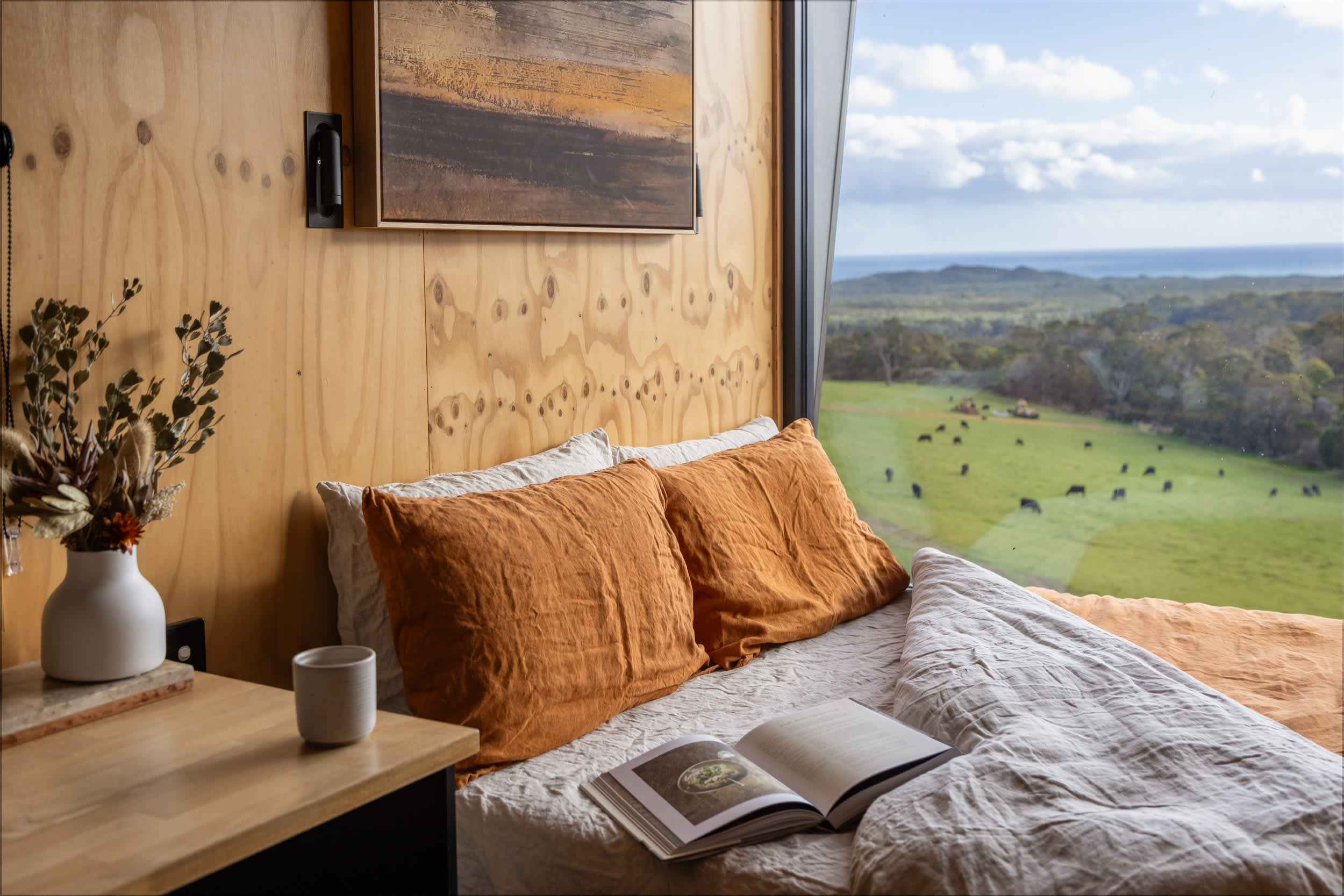 The bedroom and view showing a field of cows from a Heyscape Cabin in Denmark