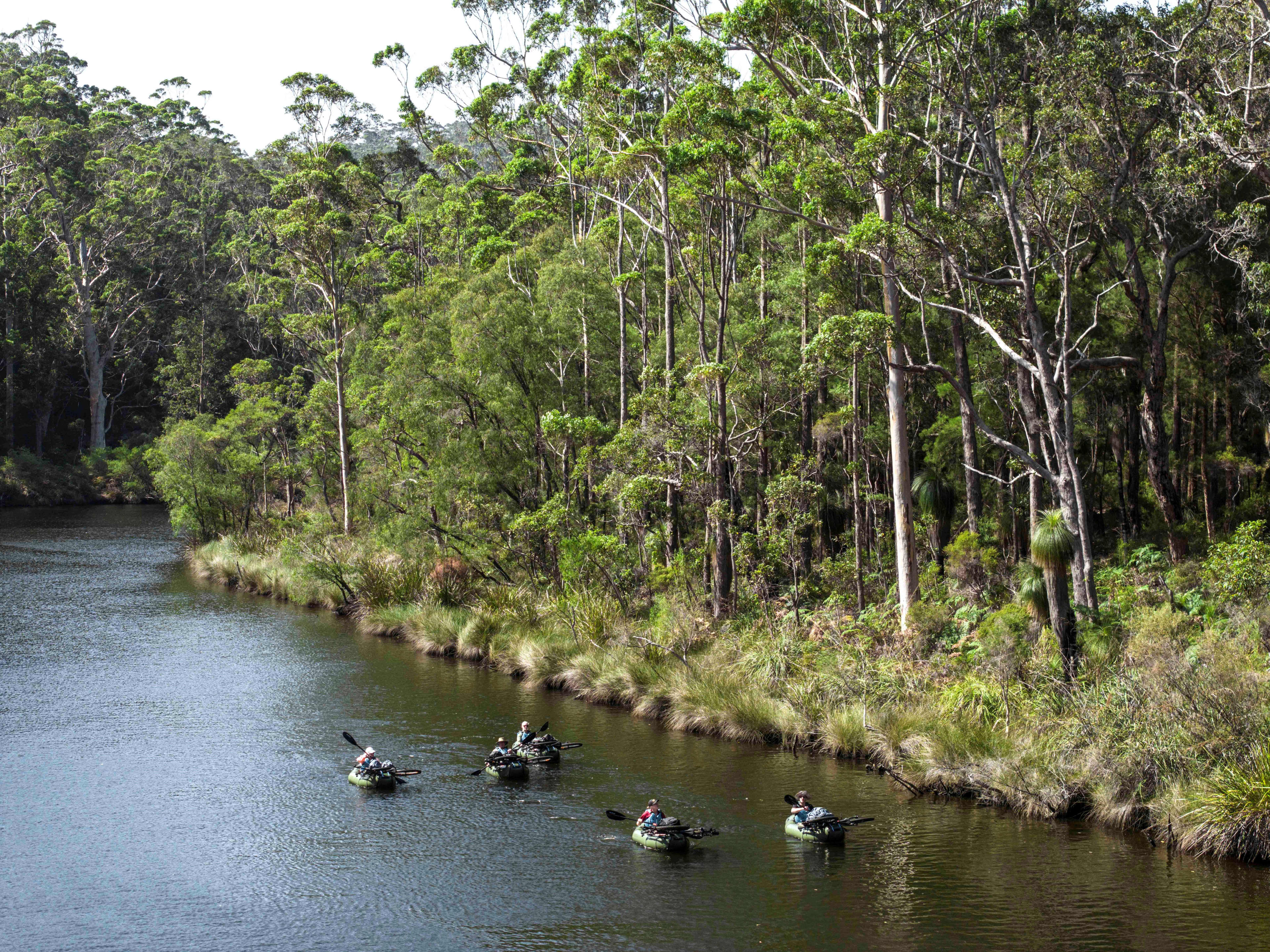 People paddling inflatable kayaks with bikes strapped to the kayak