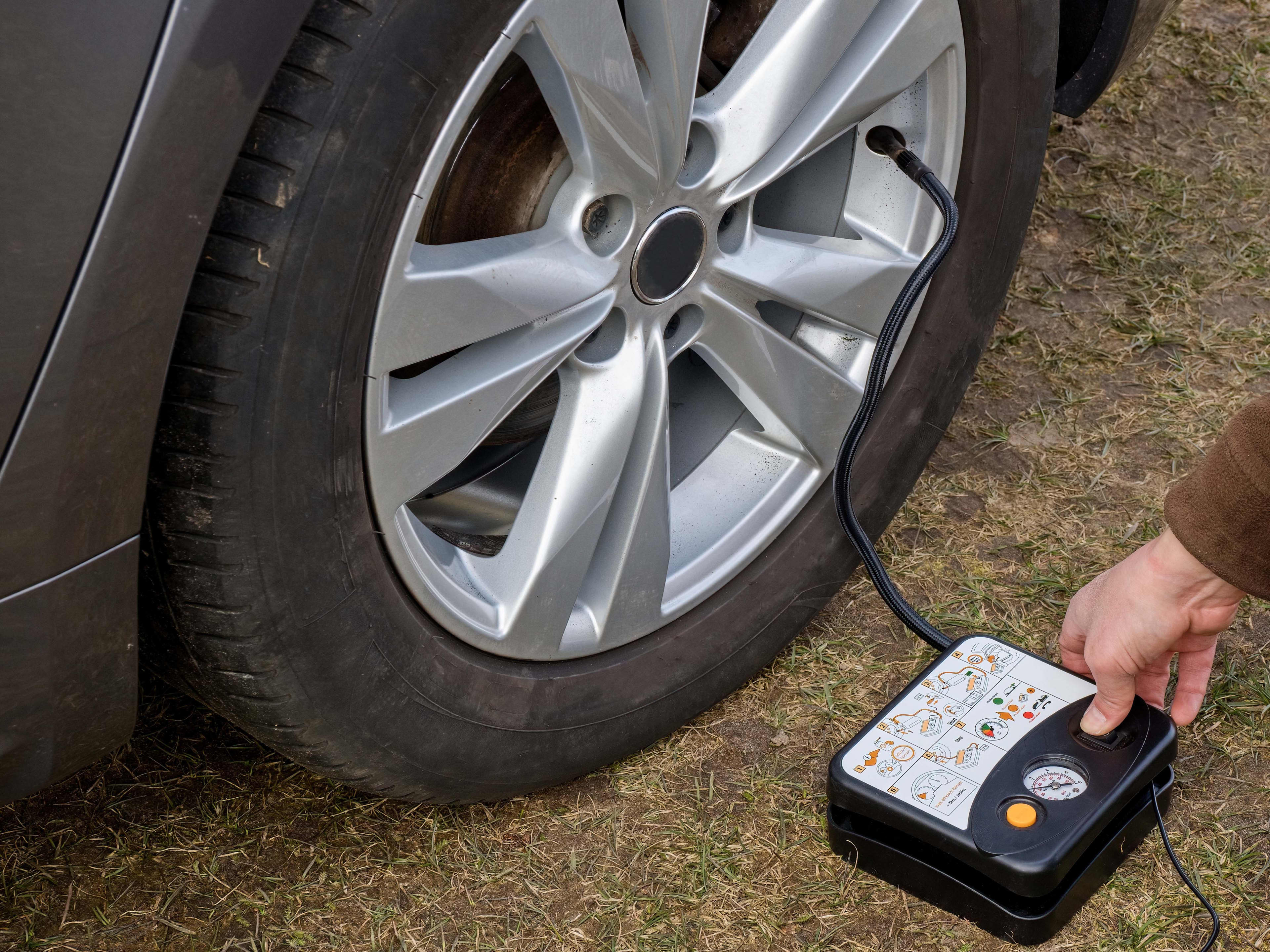 A person inflating a tyre with an inflator kit tool