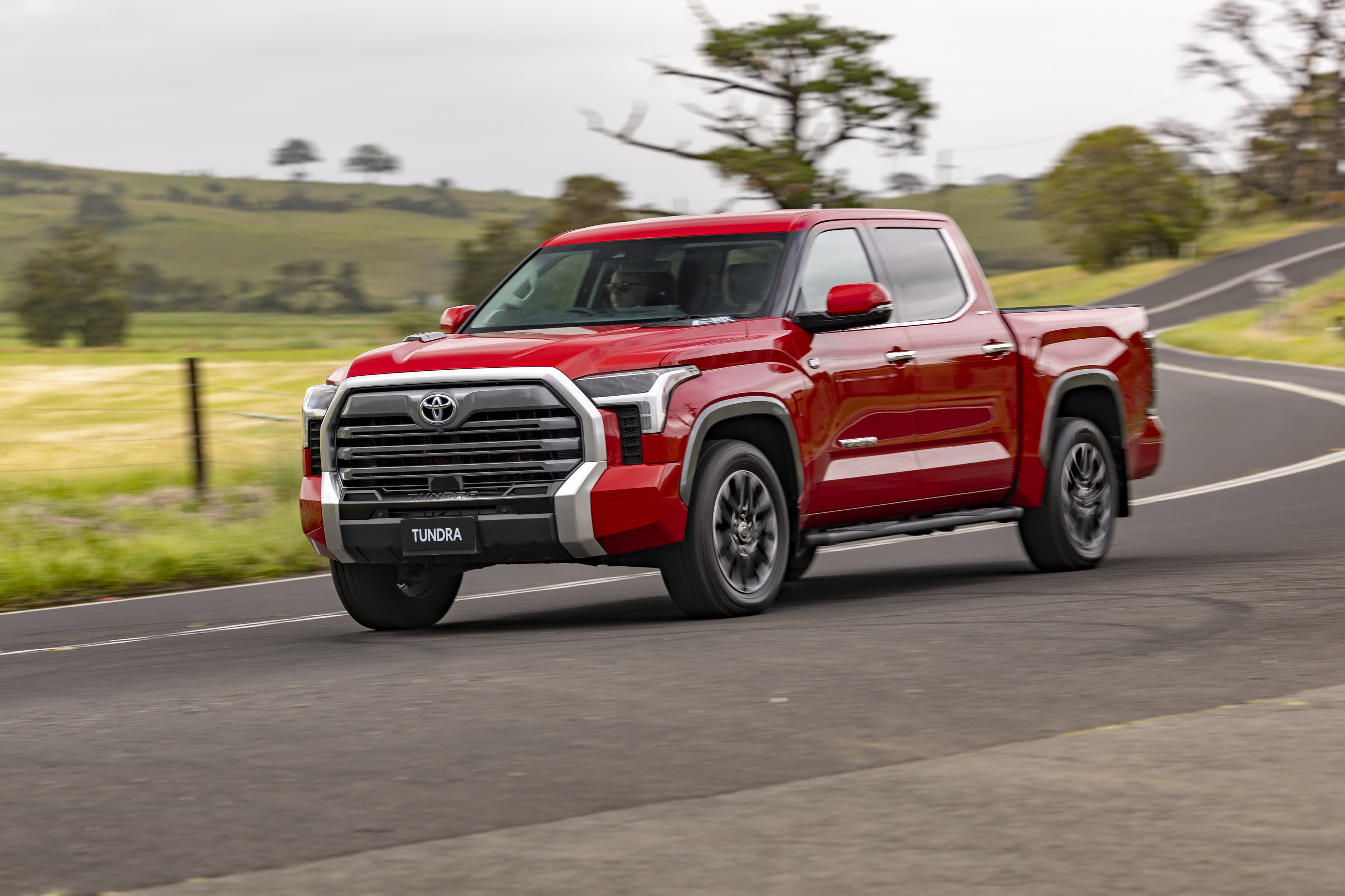 A red Toyota Tundra pickup truck driving on regional Australian roads