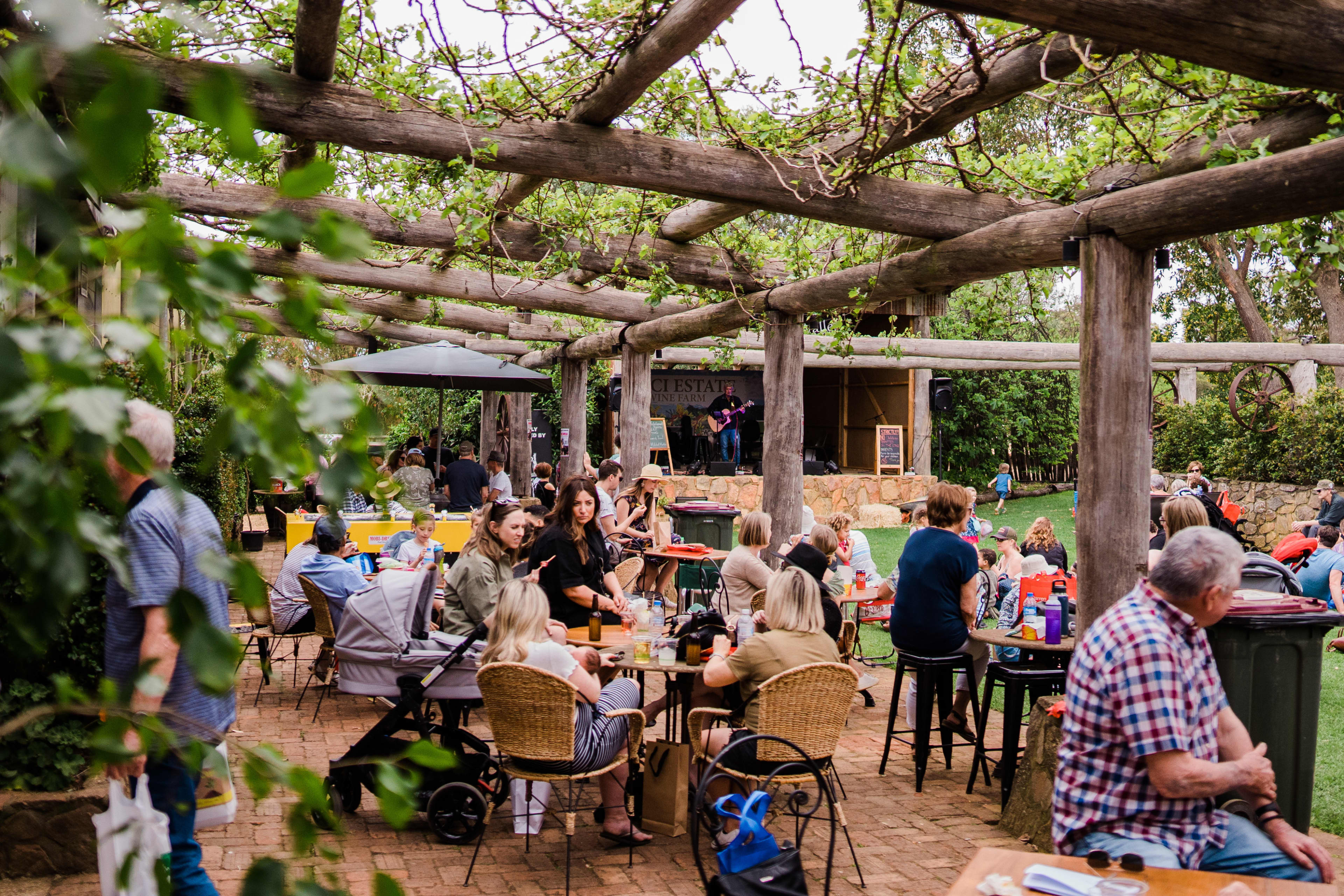 People sitting outdoors at event eating food and listening to music