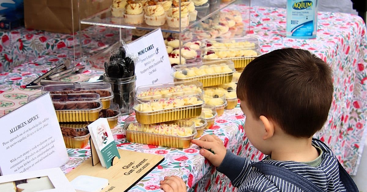Young boy looking at cupcakes at market stall