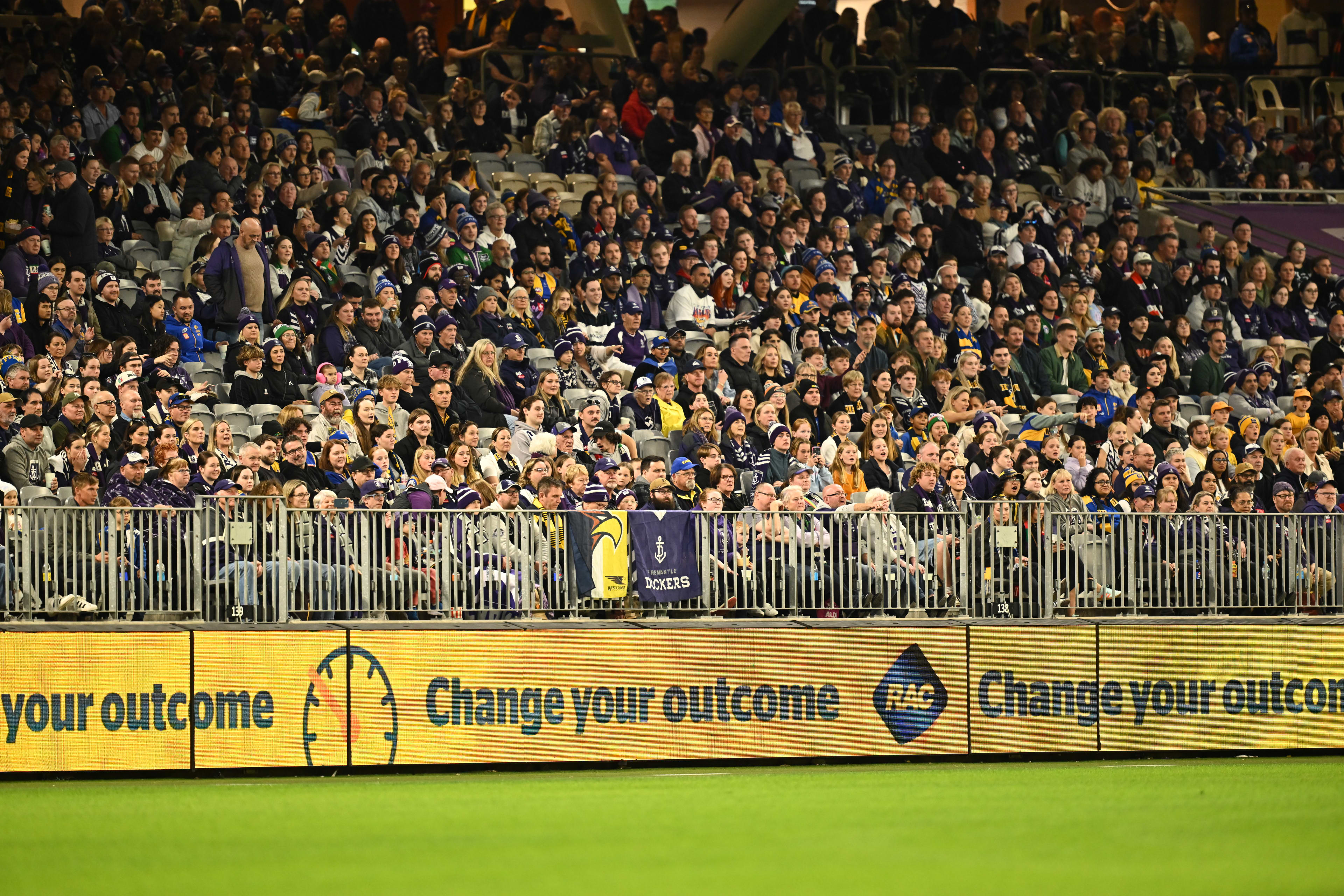 Image of the crowd at the RAC derby 61. Below the crowd is a yellow digital banner that reads "change your outcome" with the RAC logo.