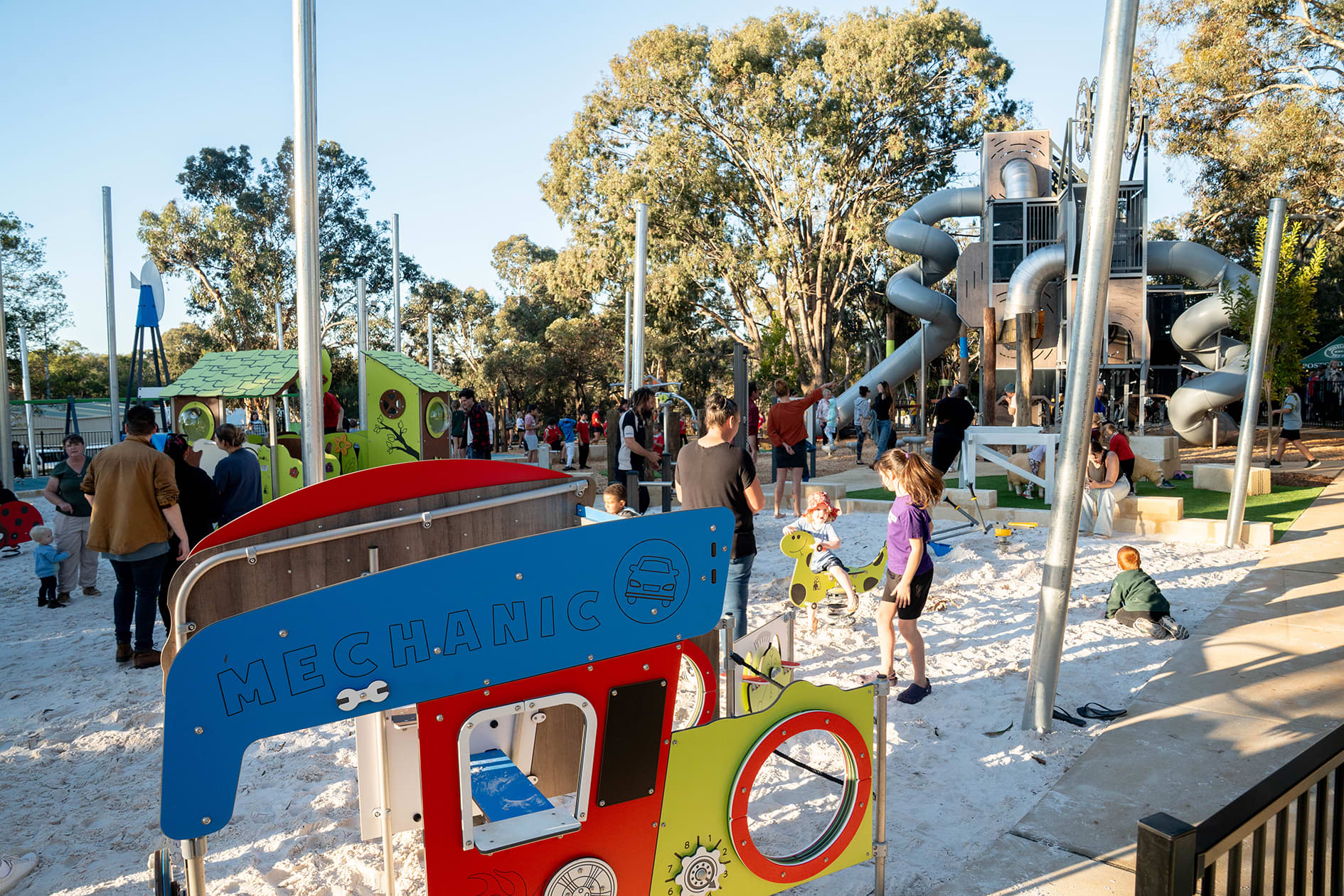 Children playing in playground with giant tower and slides and mechanic toy play equipment