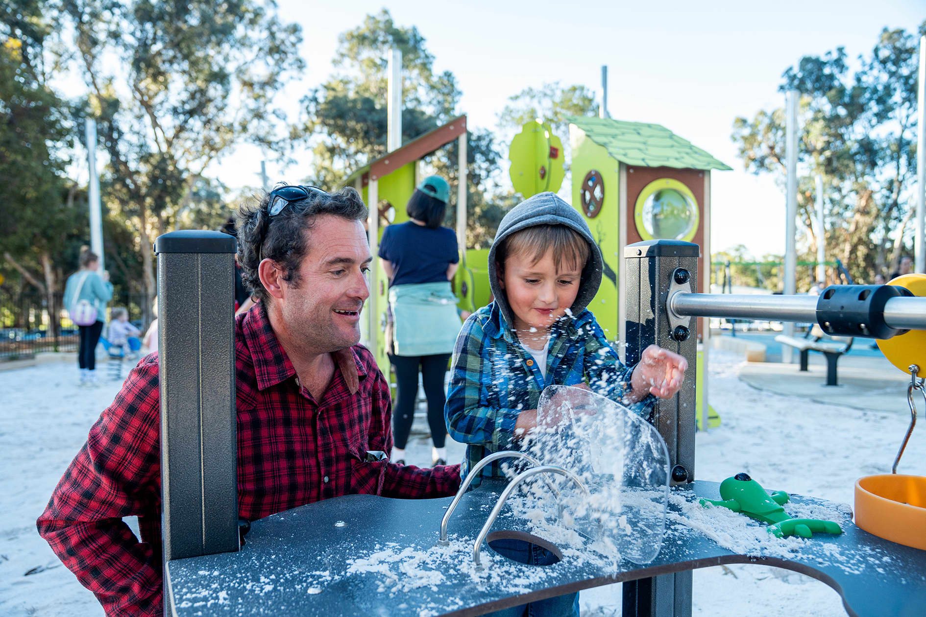 Father and son playing with sand equipment at playground