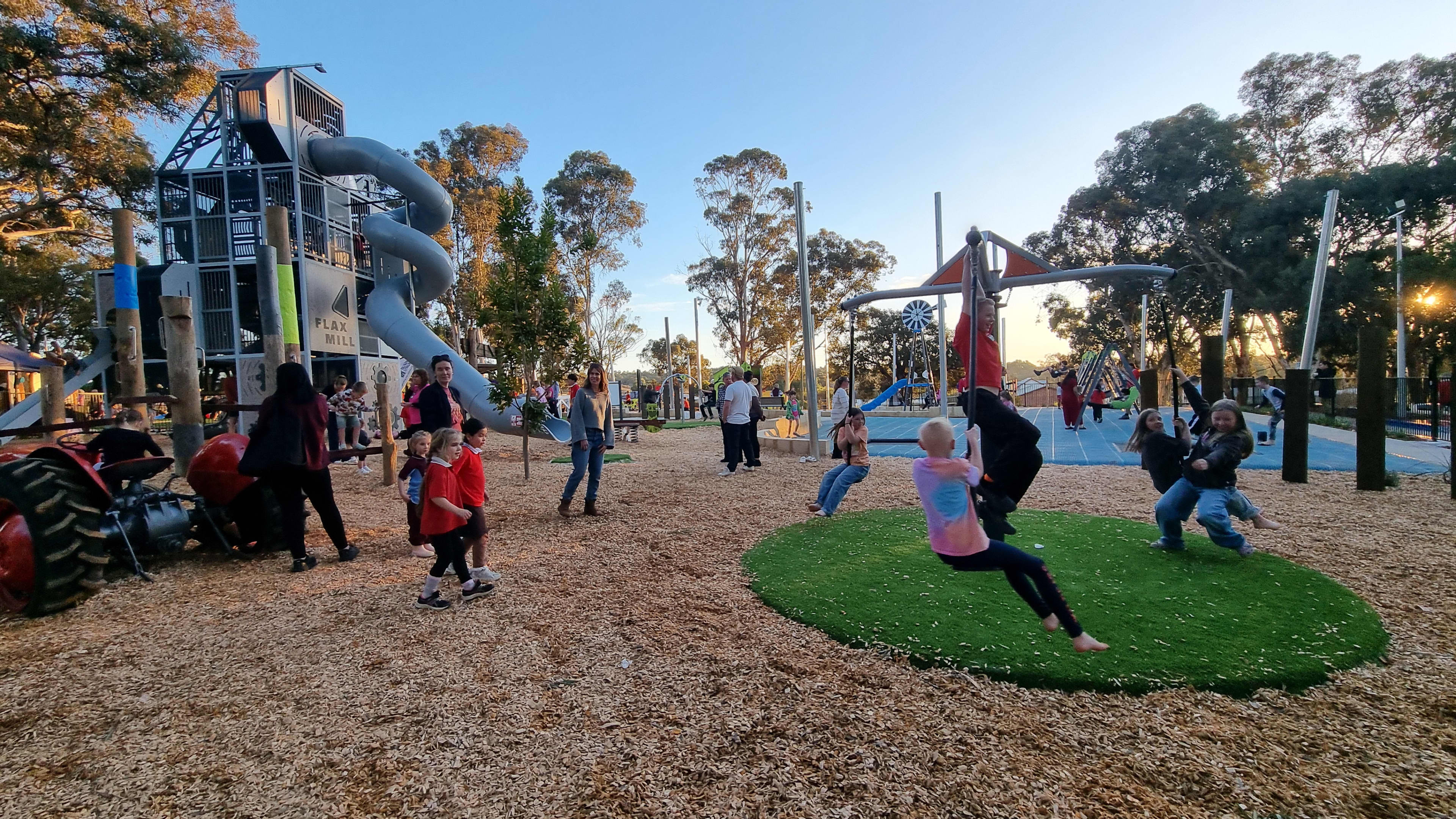 Children playing on play equipment with a tractor and slide in the background