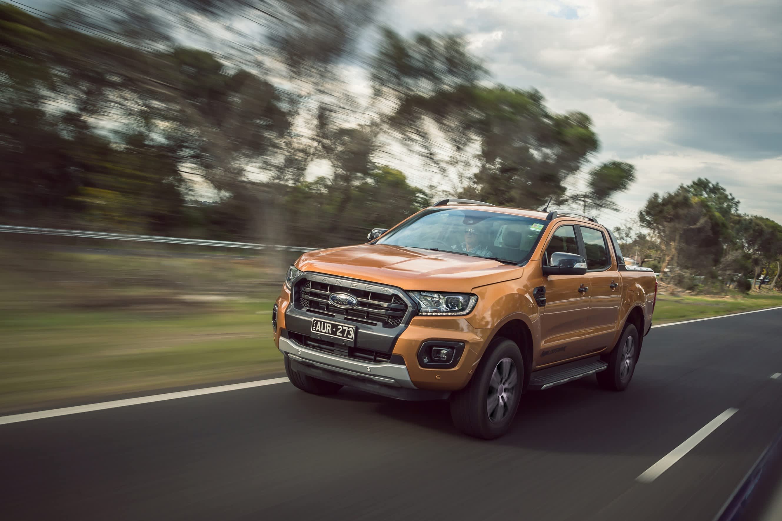An orange Ford Ranger driving on a country road