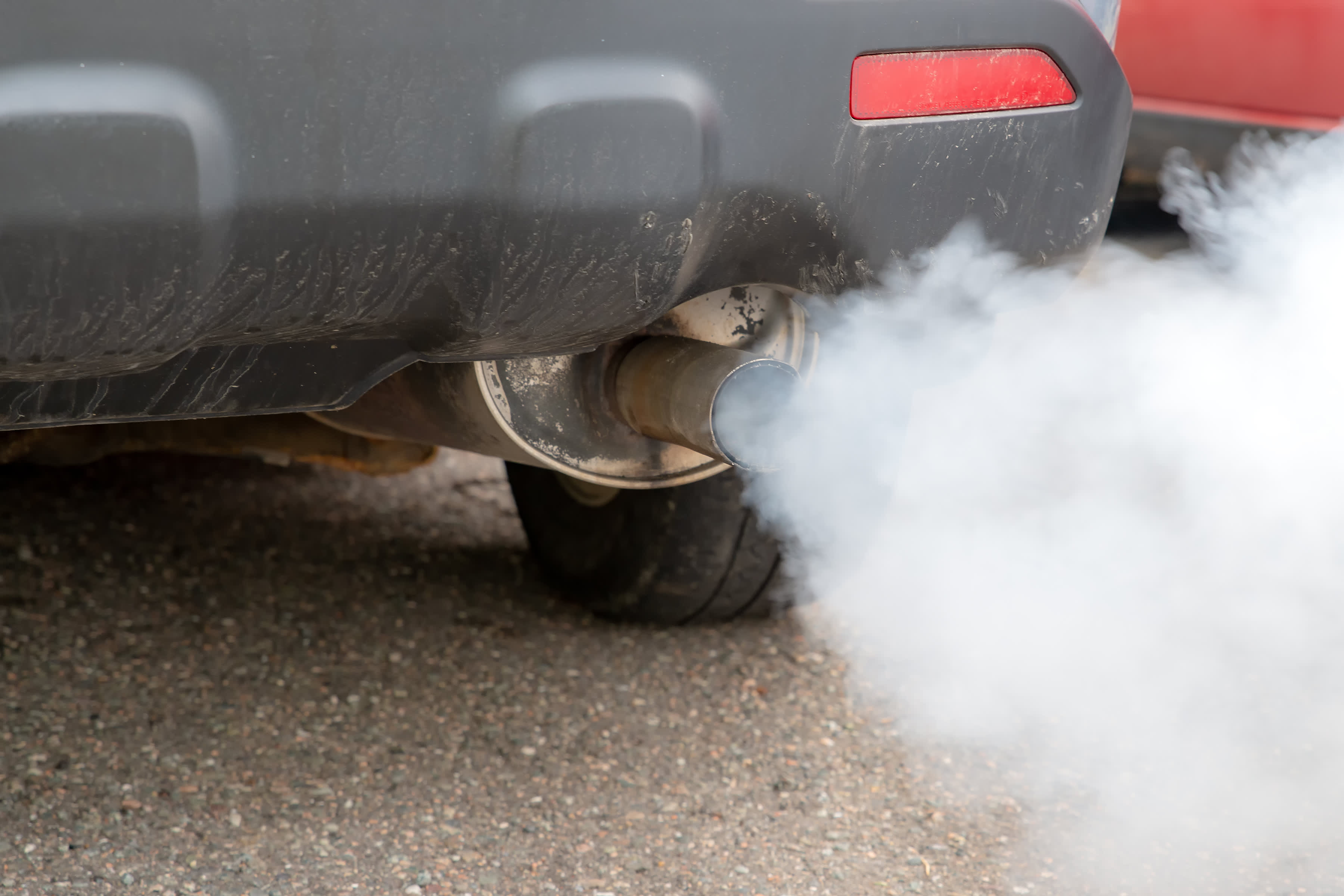 A close up of a car exhaust pipe emitting smoke.