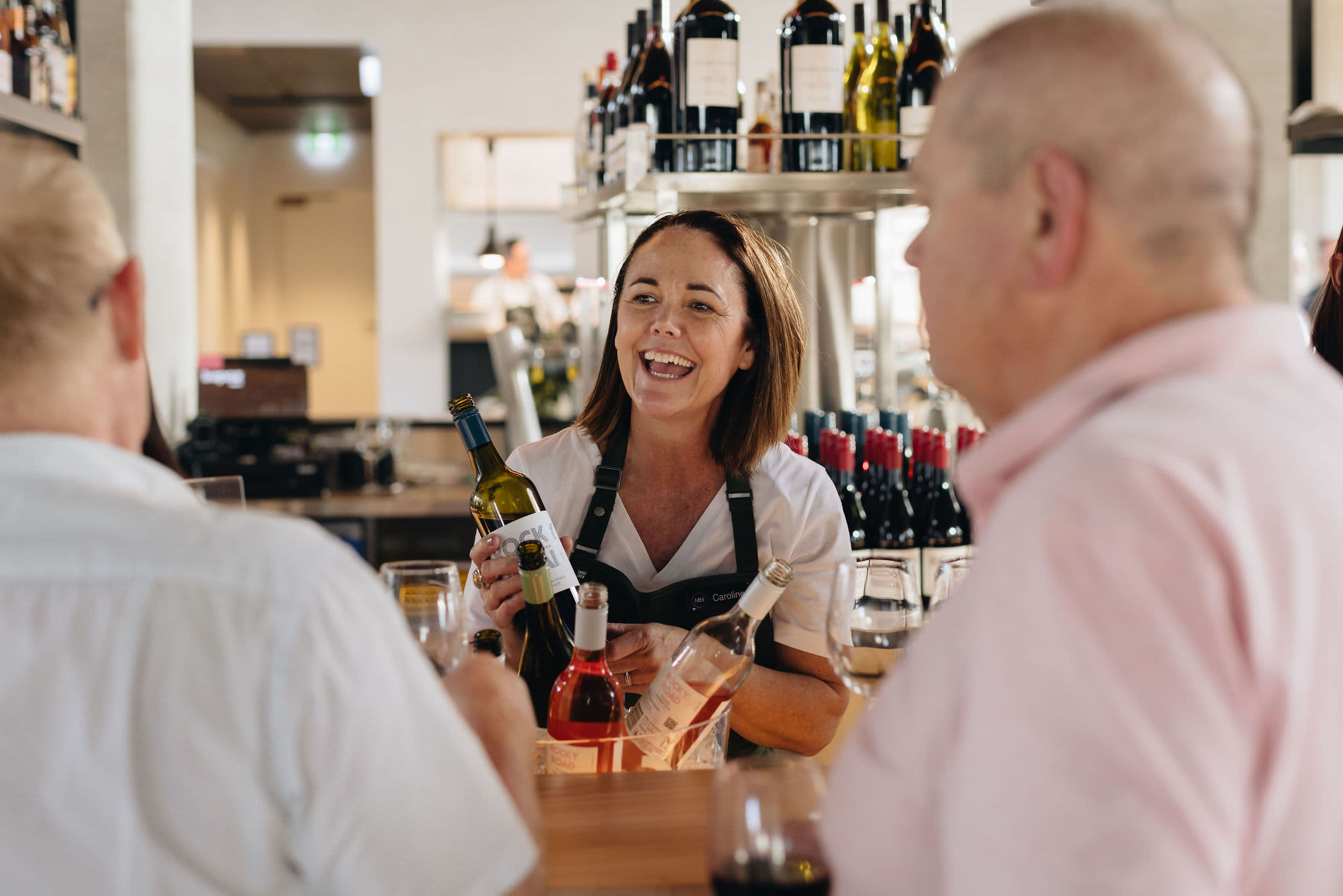 Staff member at Vintners Wine Bar helping two guests select a wine to try at bar