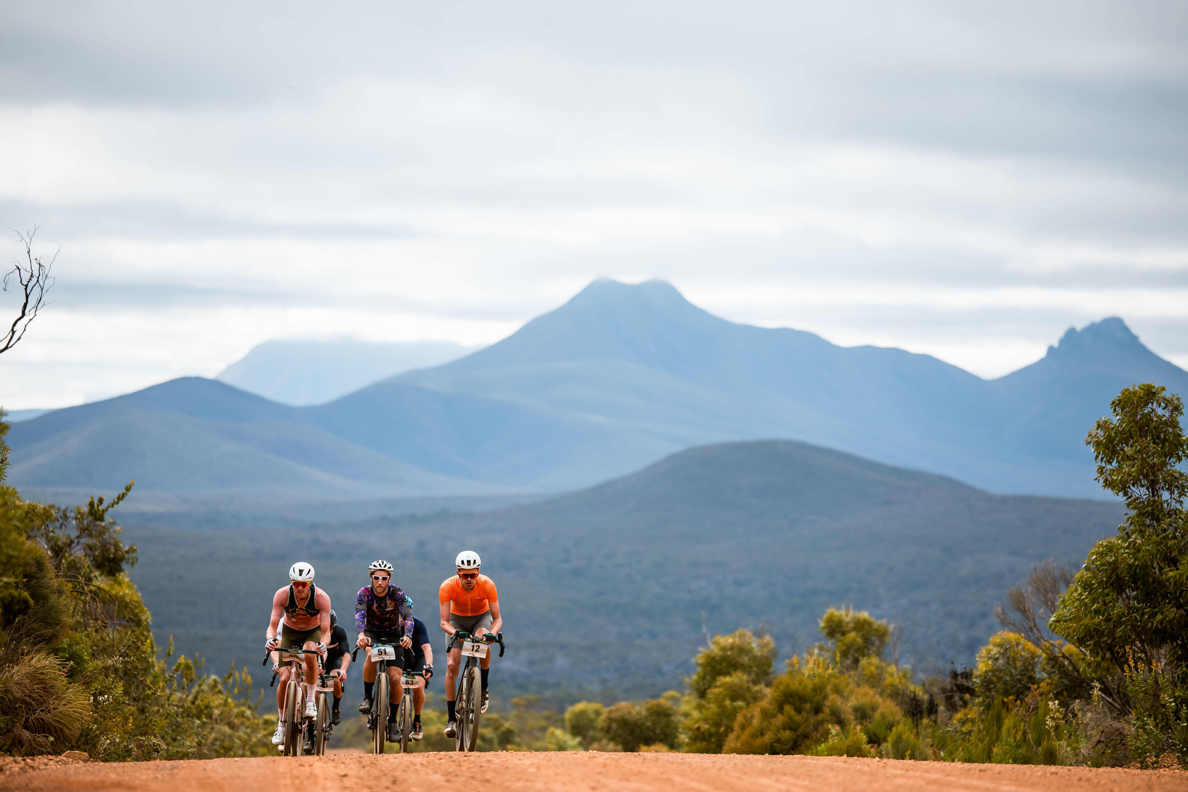 Five people riding bikes along trail with mountains in the background