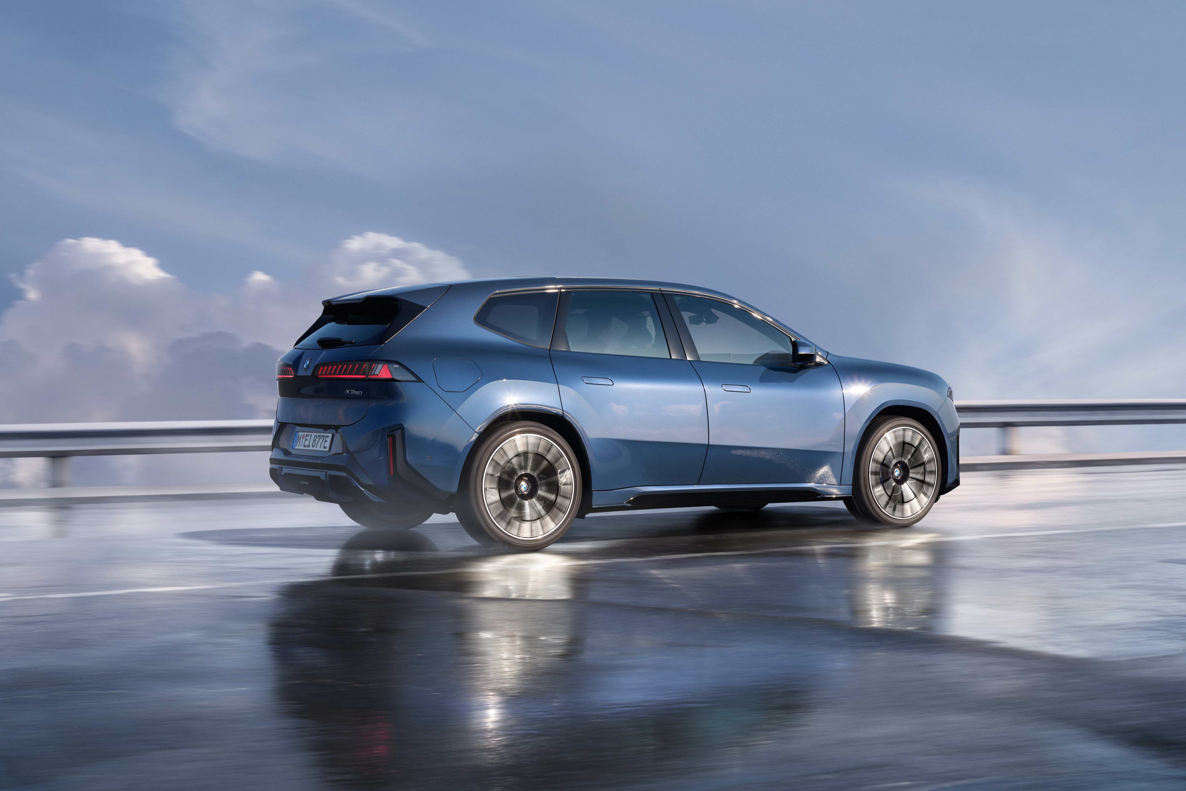 A blue BMW iX3 on a wet road