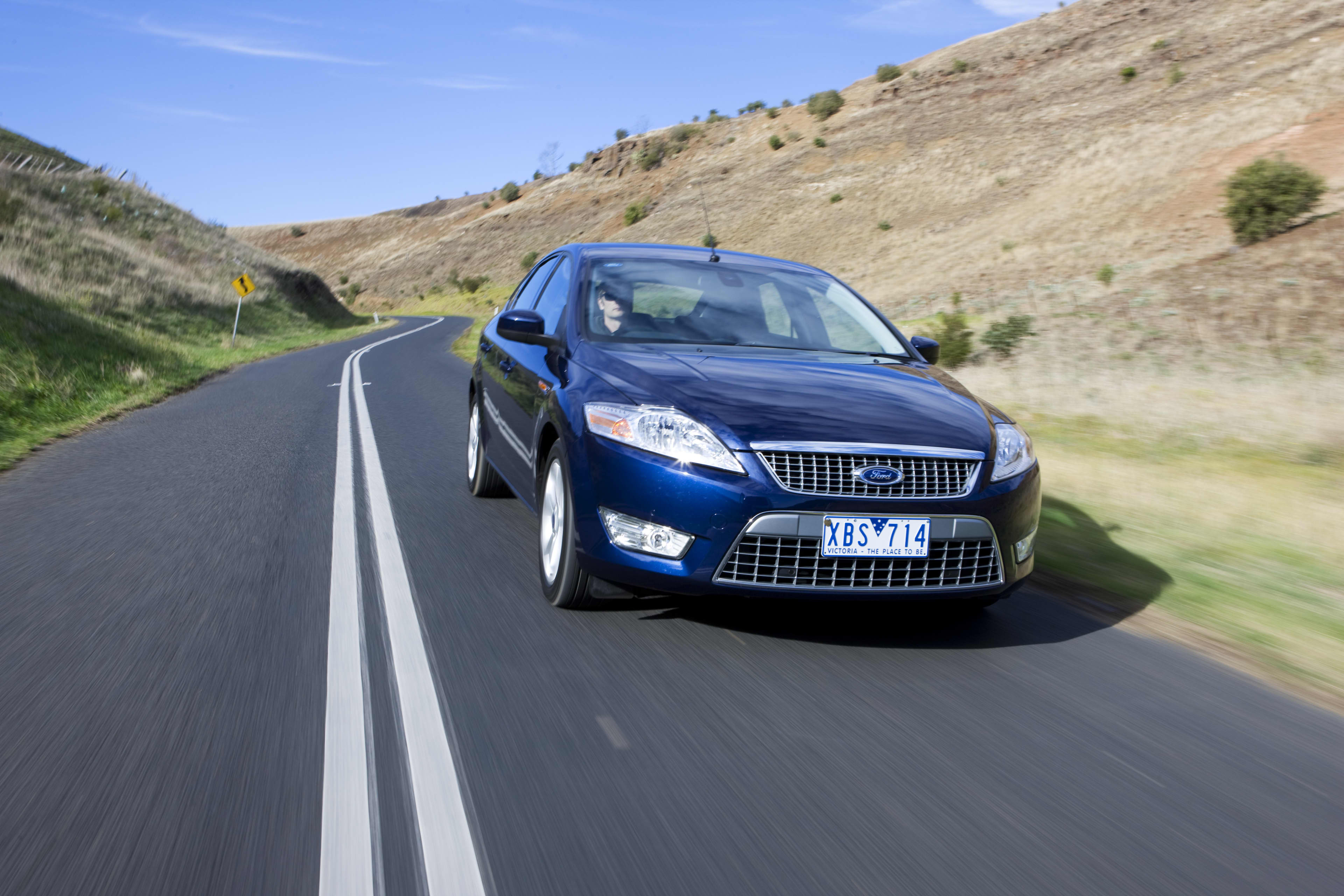 A dark blue Ford Mondeo driving on a country road.