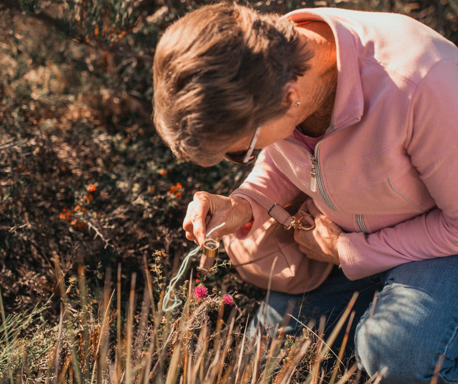 Woman crouched over looking at wildflowers