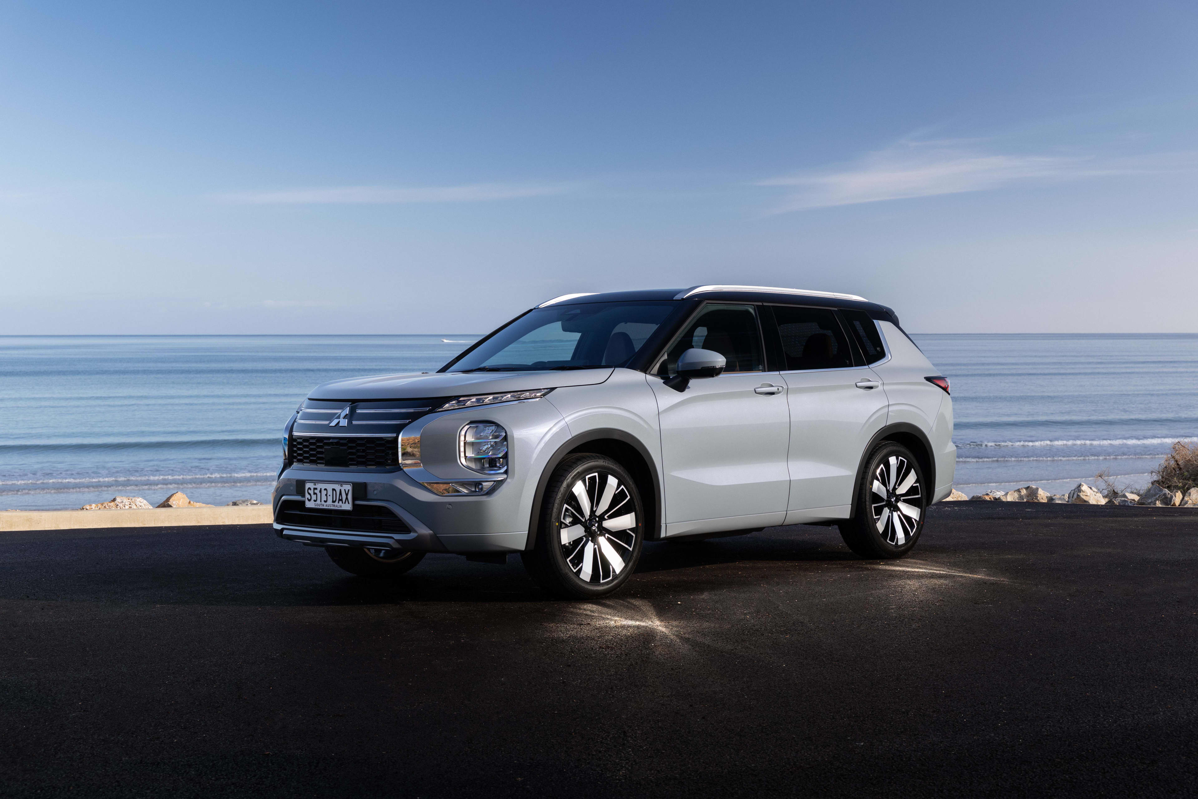 A white Mitsubishi Outlander PHEV parked near a beach