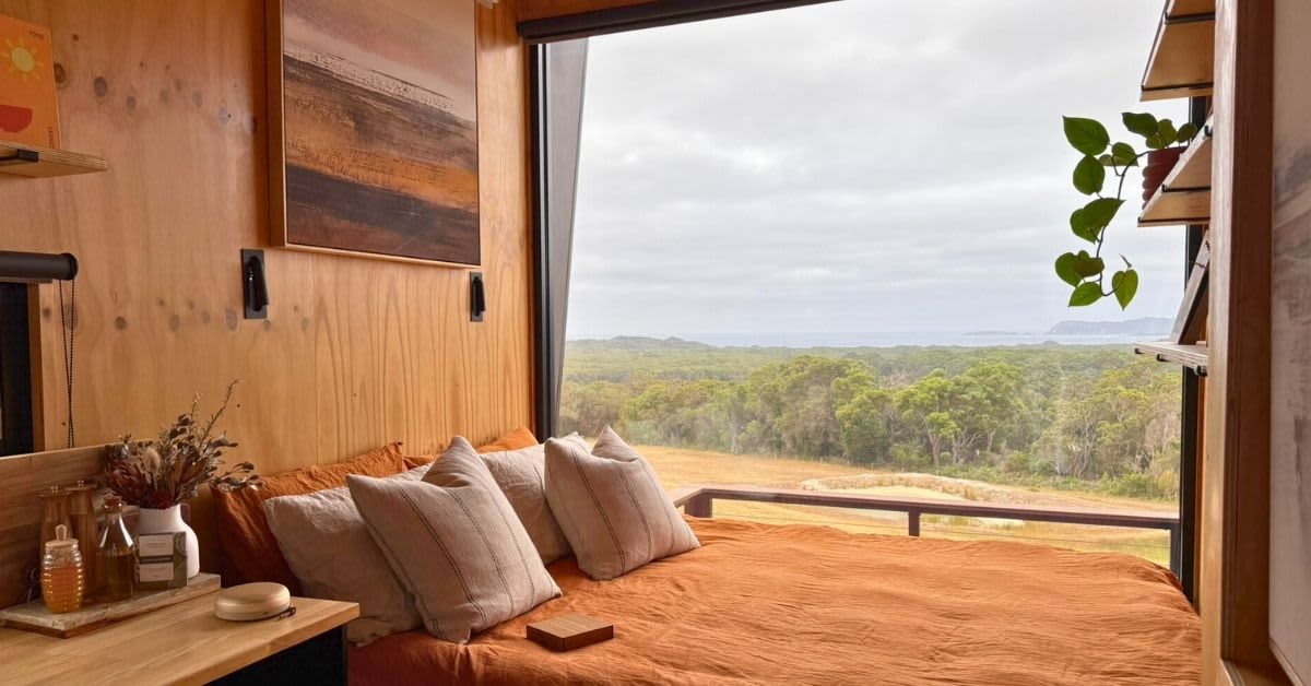 Bed in tiny cabin overlooking ocean and forest views