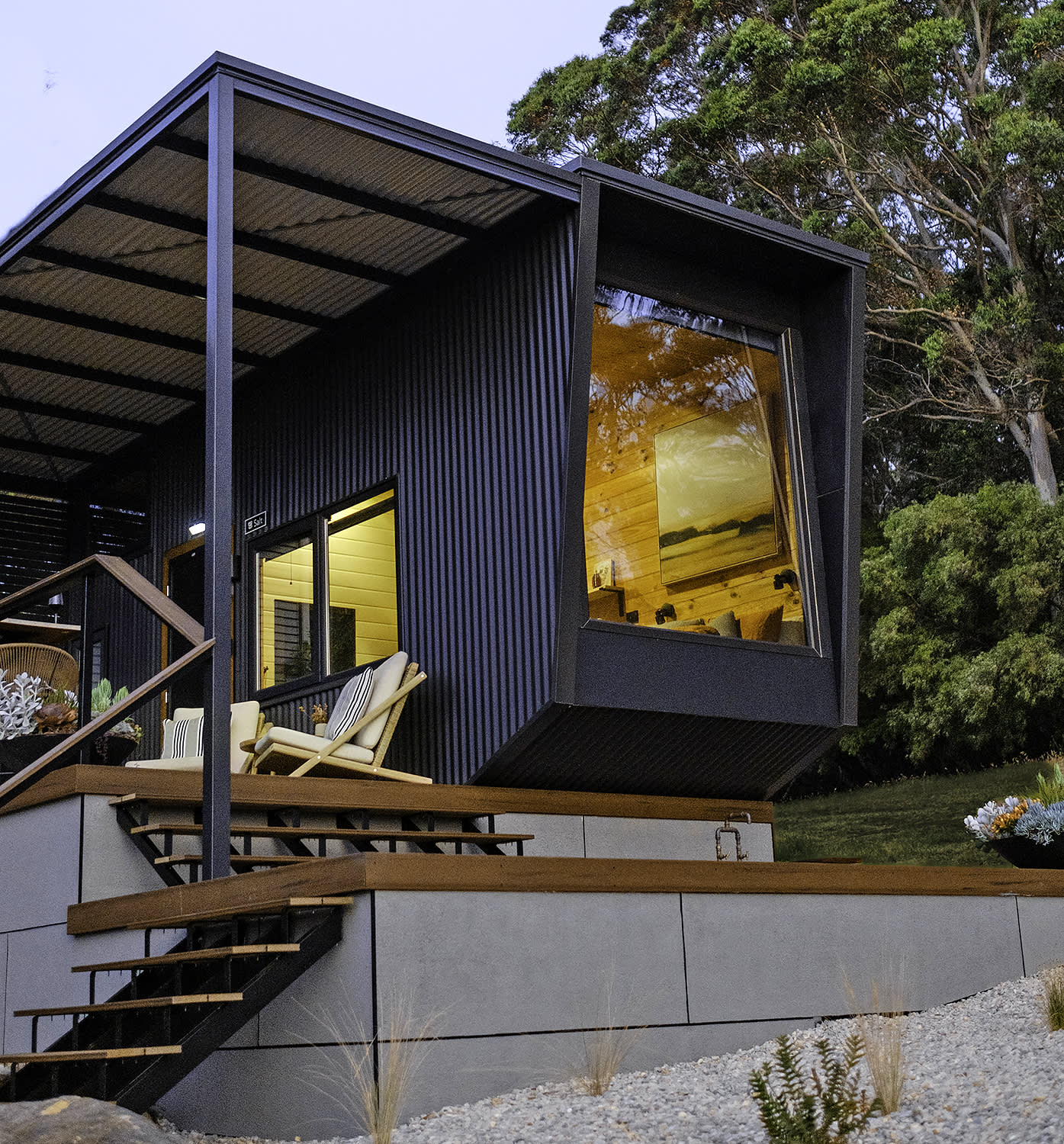 The modern exterior of a tiny cabin located close to tall trees