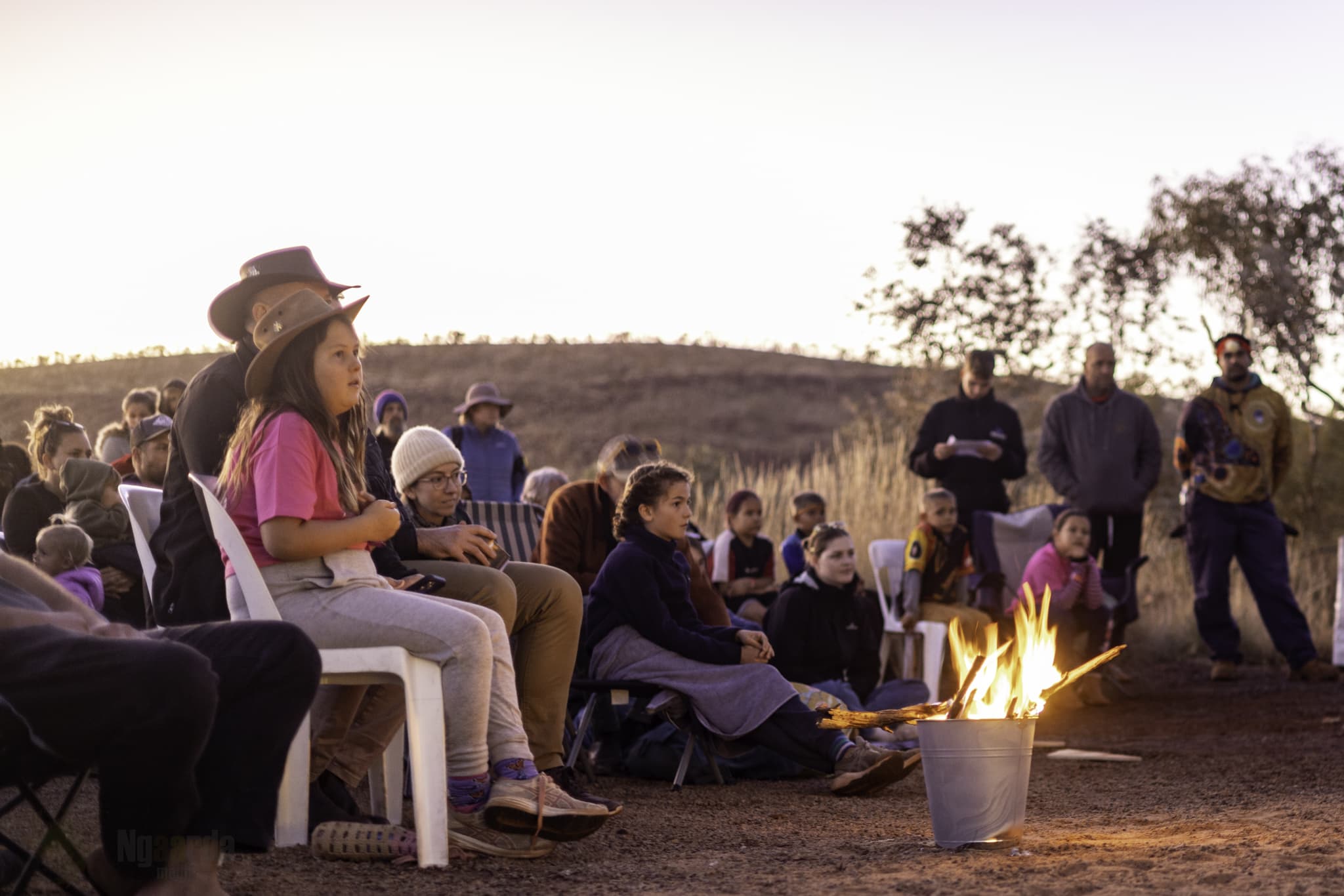 People gather around a fire in an outback setting